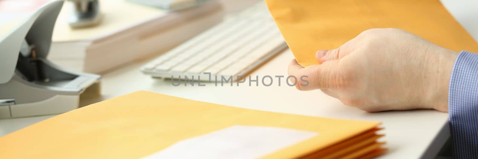 Businessman takes out documents from yellow envelope by kuprevich
