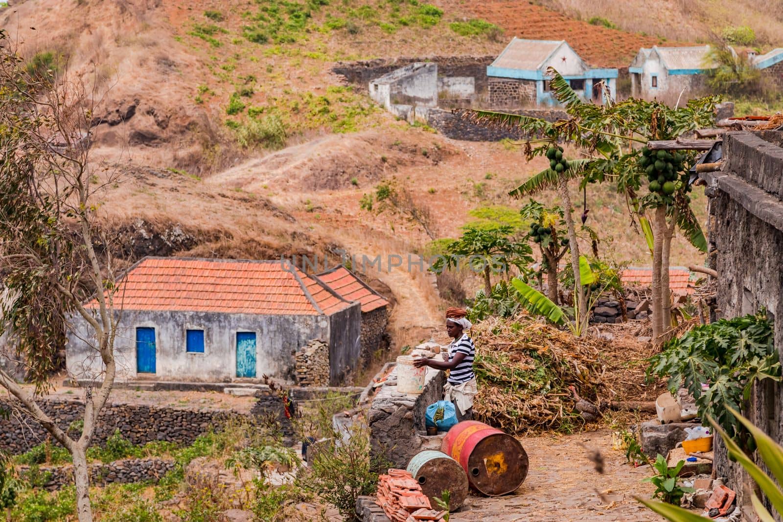 A woman at work in front of a simple house in the rough and mountainous center of Santiago Island, Cape Verde Islands, Macaronesia