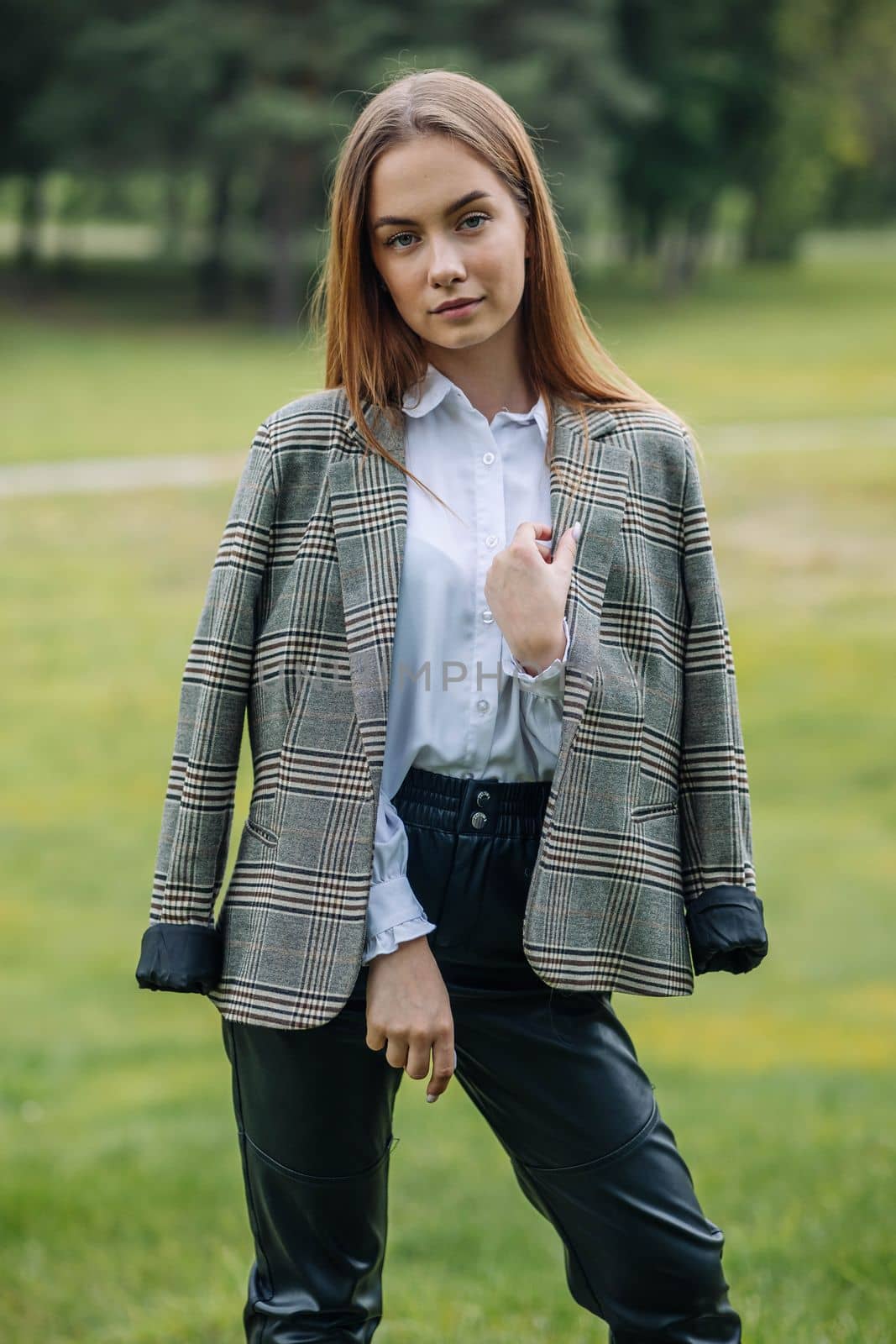 A young girl in a jacket poses in a park in the summer. by DovidPro