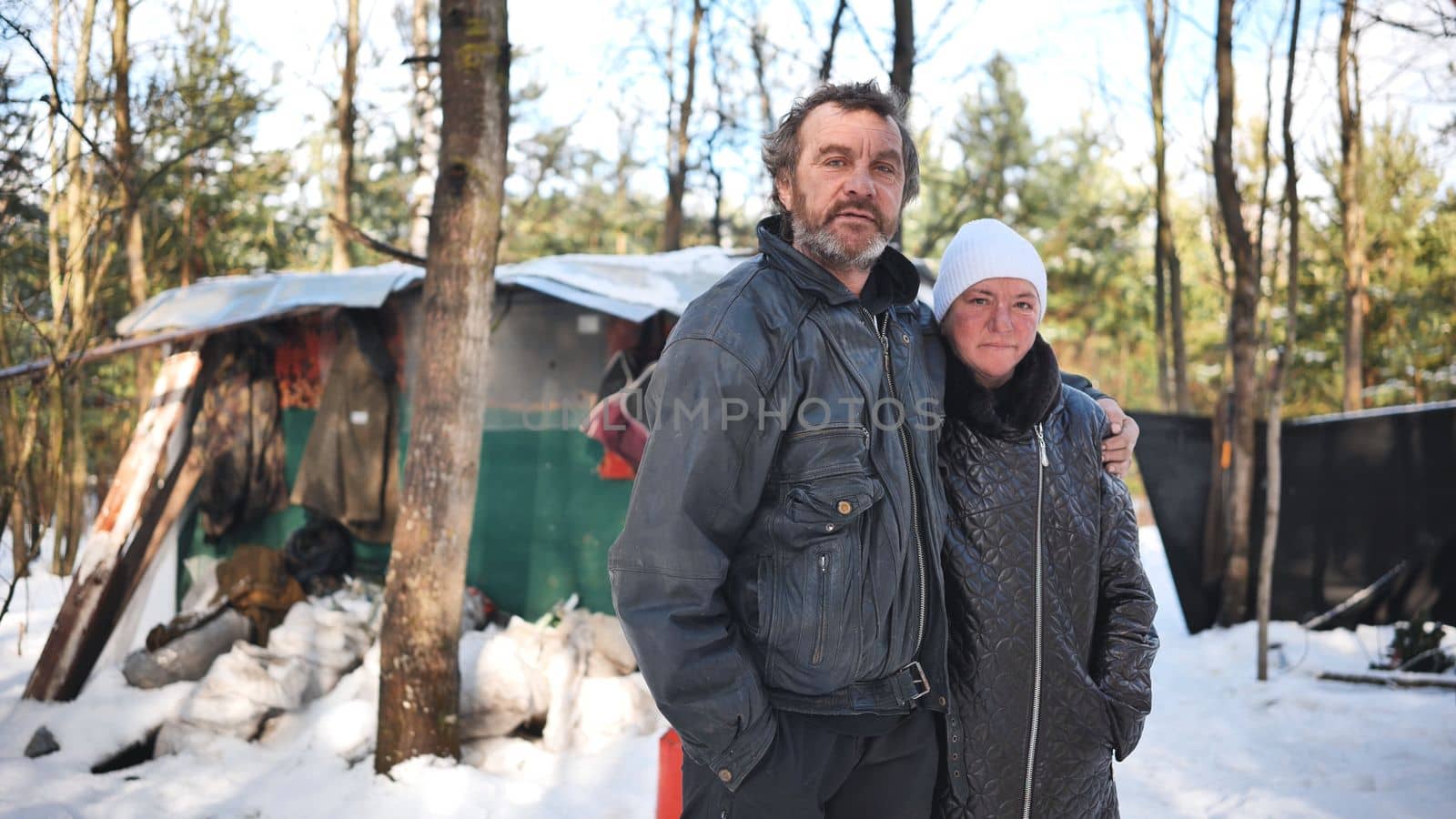 A homeless woman and a man pose in the woods in winter