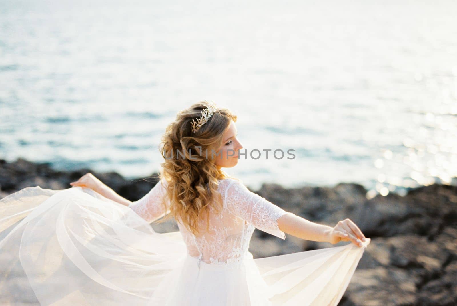 Bride stands with her arms outstretched with the overskirts of her dress. High quality photo