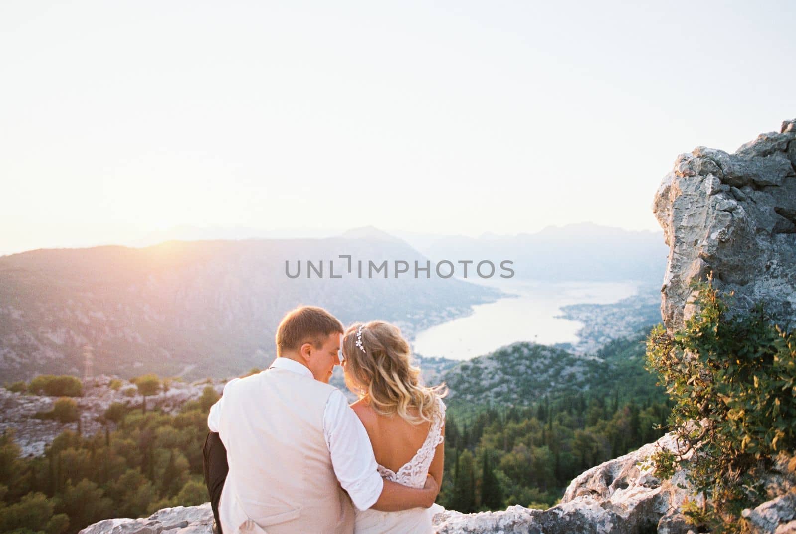 Bride and groom sit hugging on a mountain overlooking the Kotor Bay. Montenegro. High quality photo
