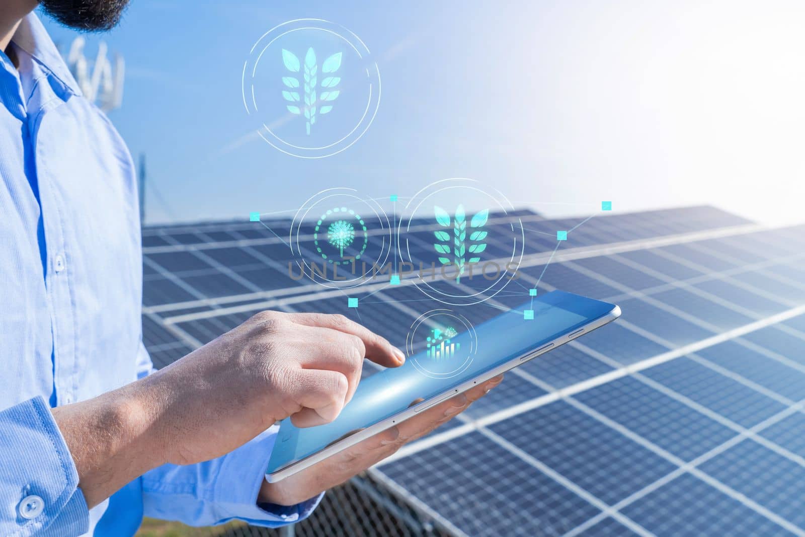 Unrecognizable engineer with a tablet with eco holograms with photovoltaic solar panel system plant in the background. Green clean energy concept.