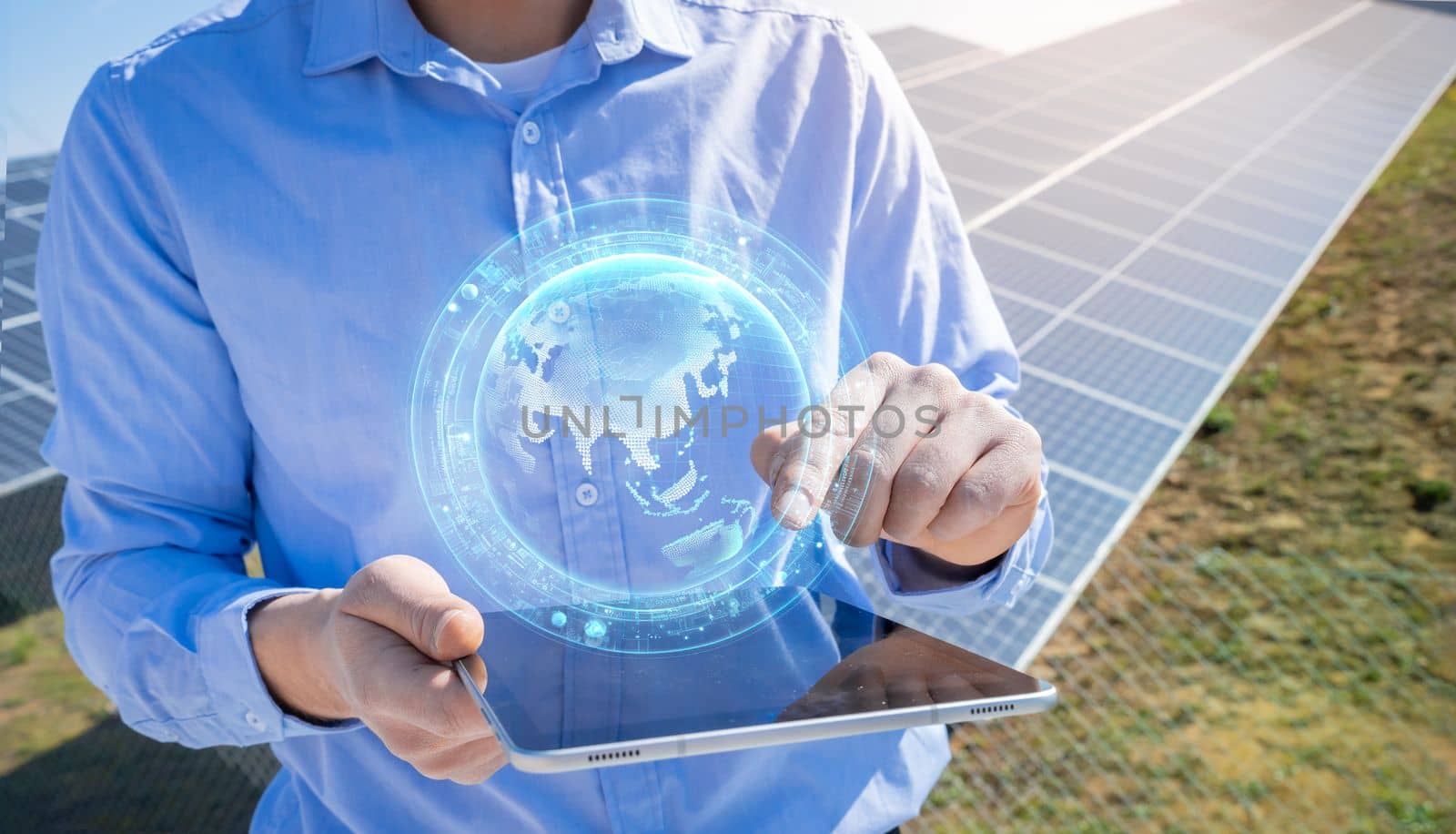 Unrecognizable engineer with a tablet with earth HUD hologram in photovoltaic solar panels plant. by PaulCarr