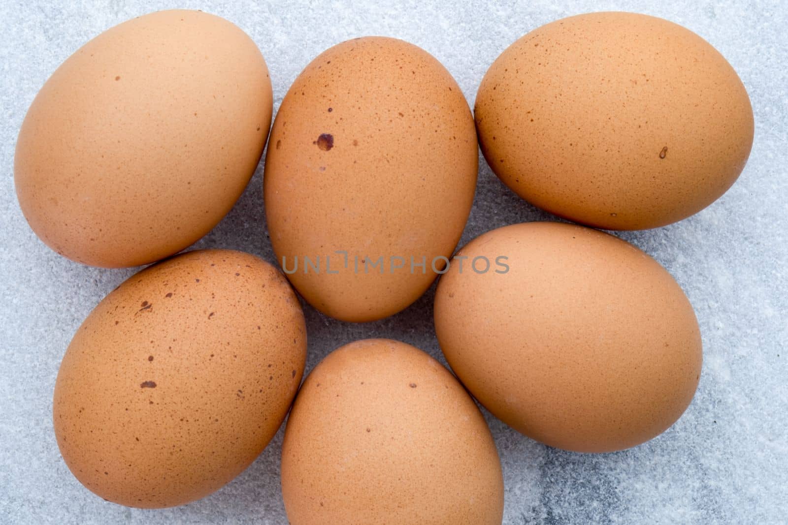 Top view of six brown speckled eggs on a marble countertop, table top, Golden Comet eggs, clean modern look. High quality photo