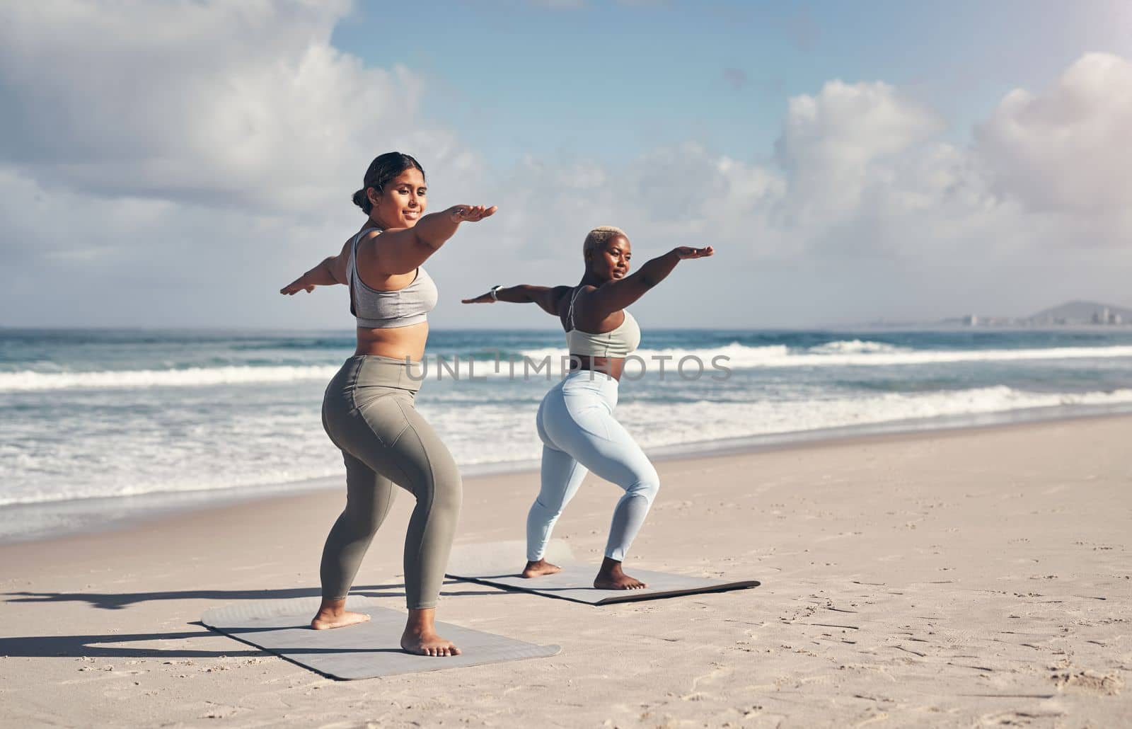 Yoga is an art that you need to practice daily. two young women practicing yoga on the beach. by YuriArcurs