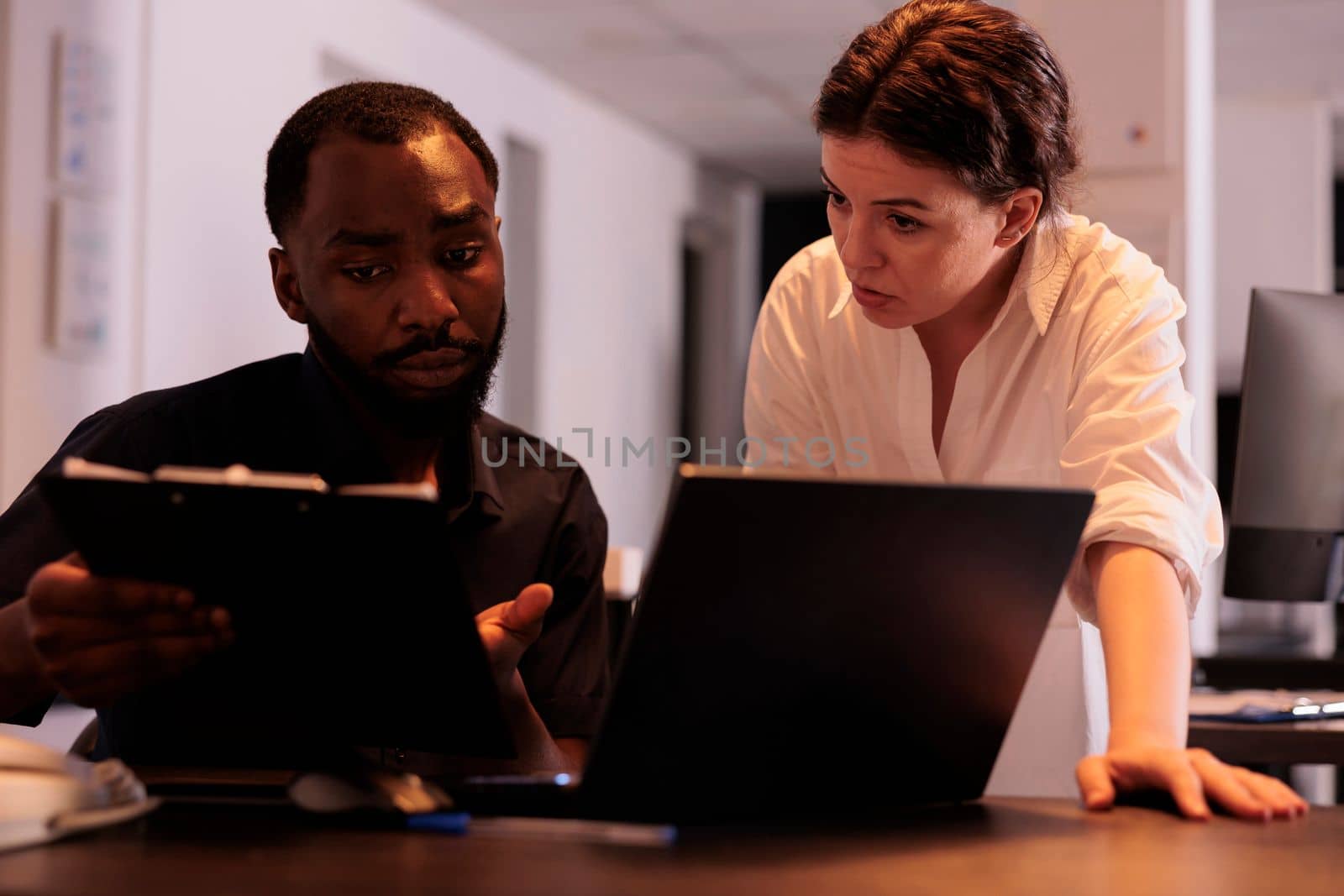 Two coworkers analyzing report statistics, working together on laptop by DCStudio
