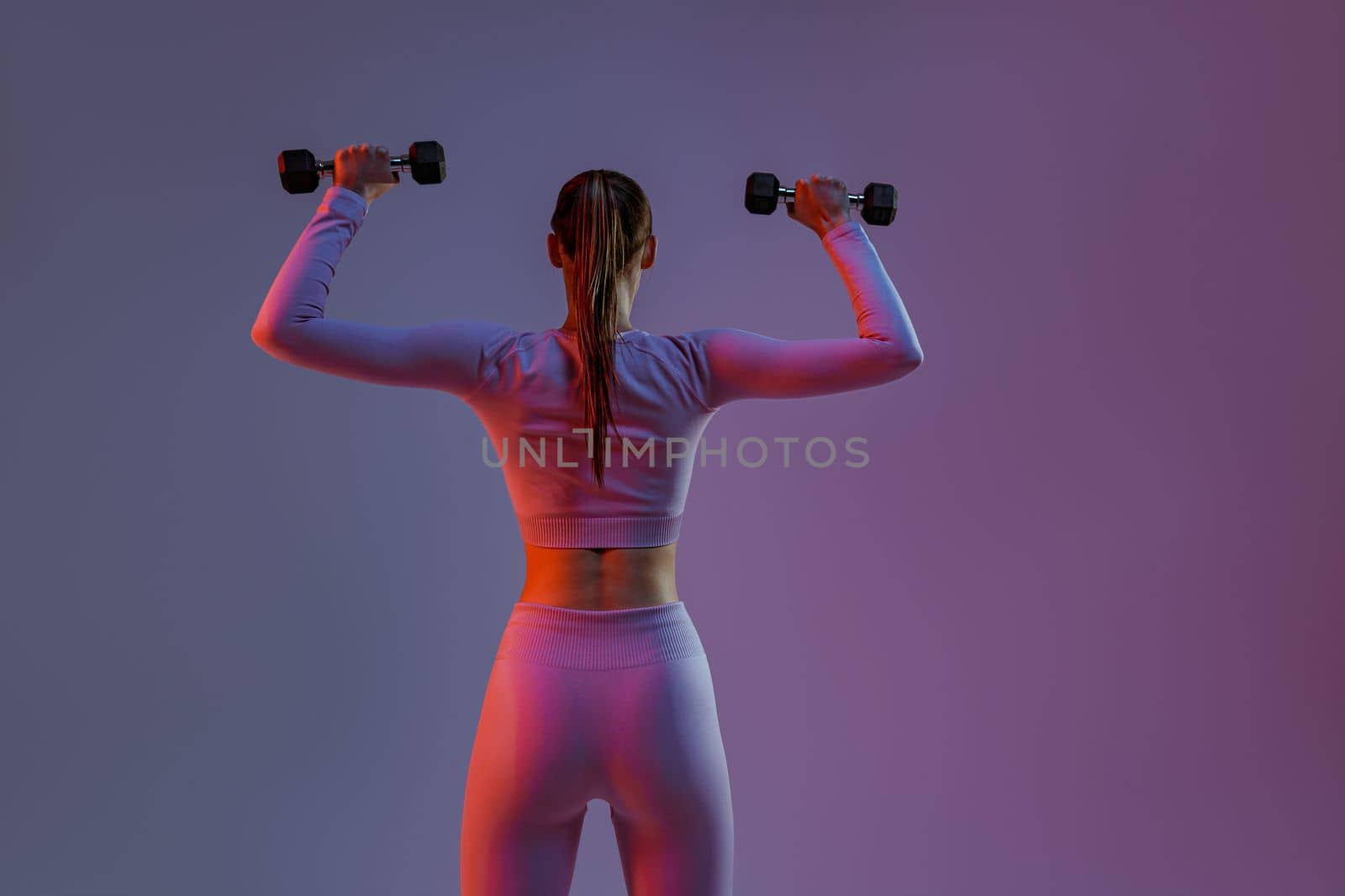 Woman doing exercises with dumbbells on studio background . Sport and healthy lifestyle