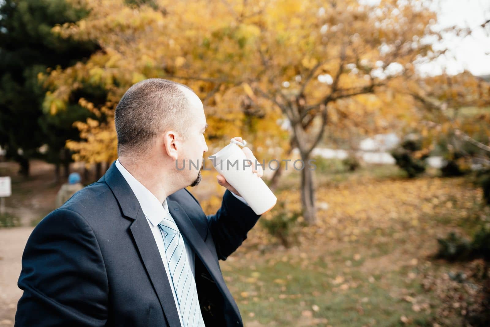 Mature entrepreneur drink coffee in autumn park. Senior executive rest in city park.
