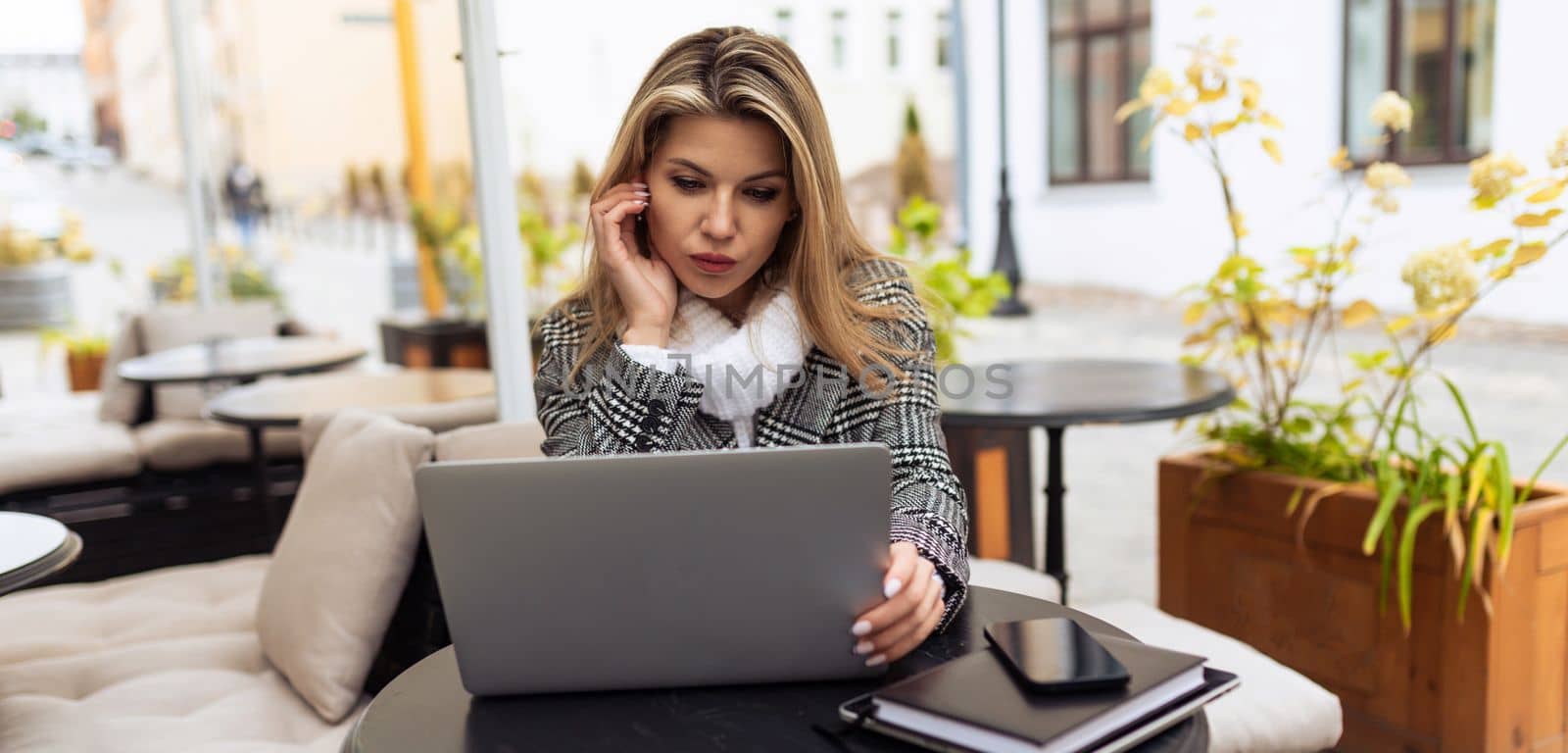 Business Caucasian woman working on laptop in cafe.