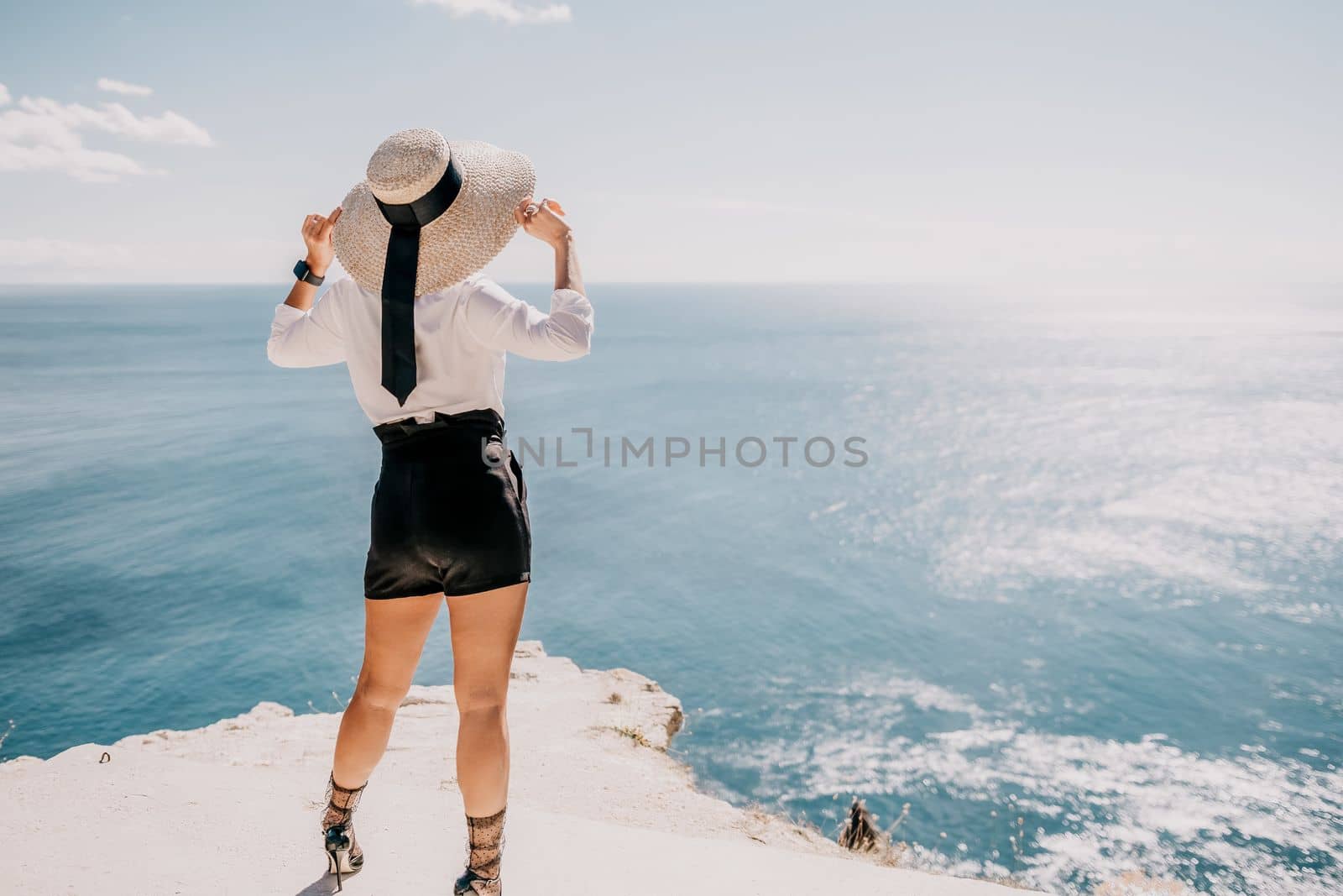 Woman sea hat. Business woman in yellow hat freelancer working over blue sea beach. Girl relieves stress from work. Freelance, digital nomad, travel and holidays concept by panophotograph