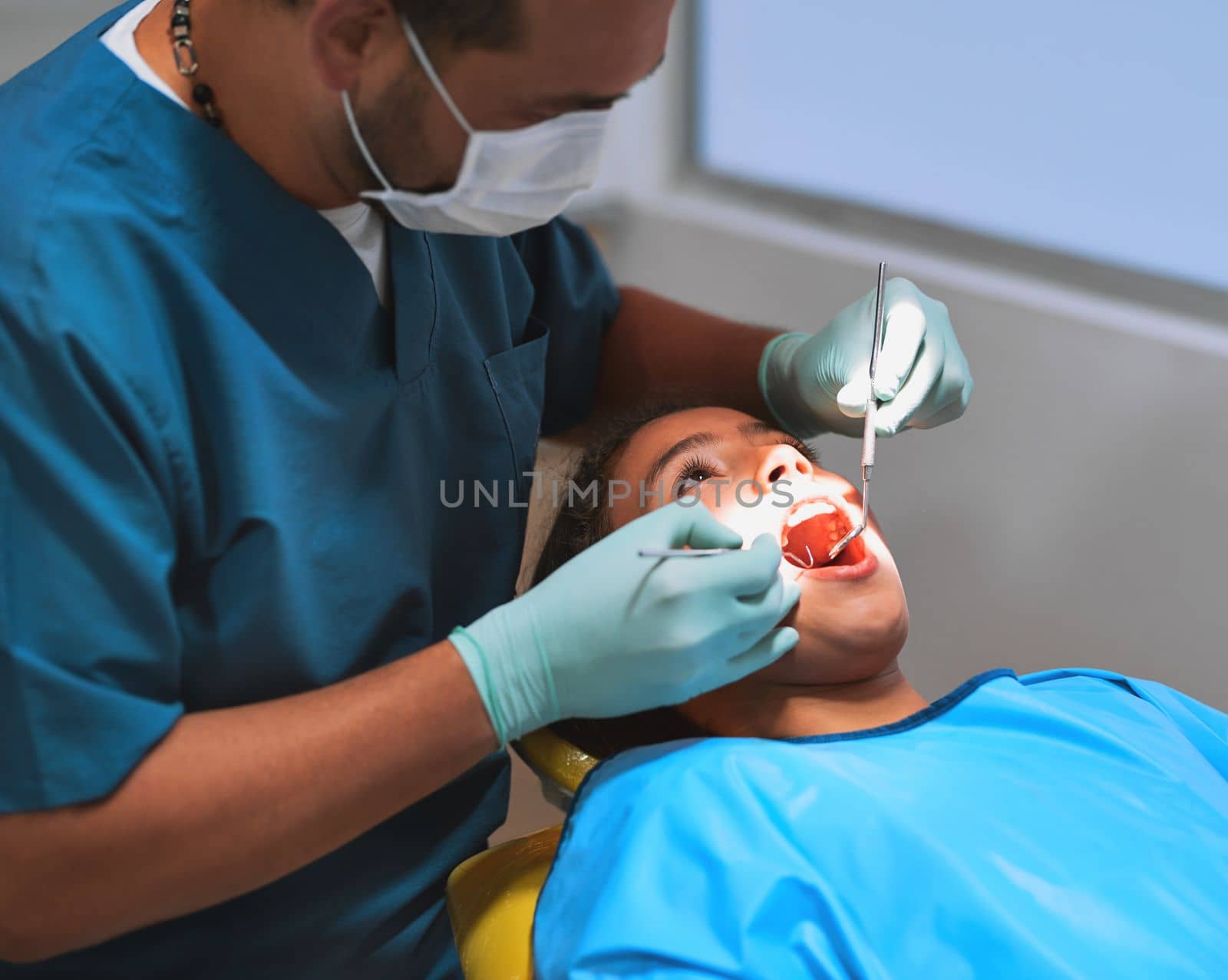 I found the problem. a young little girl lying down on a dentist chair while getting a checkup from the dentist