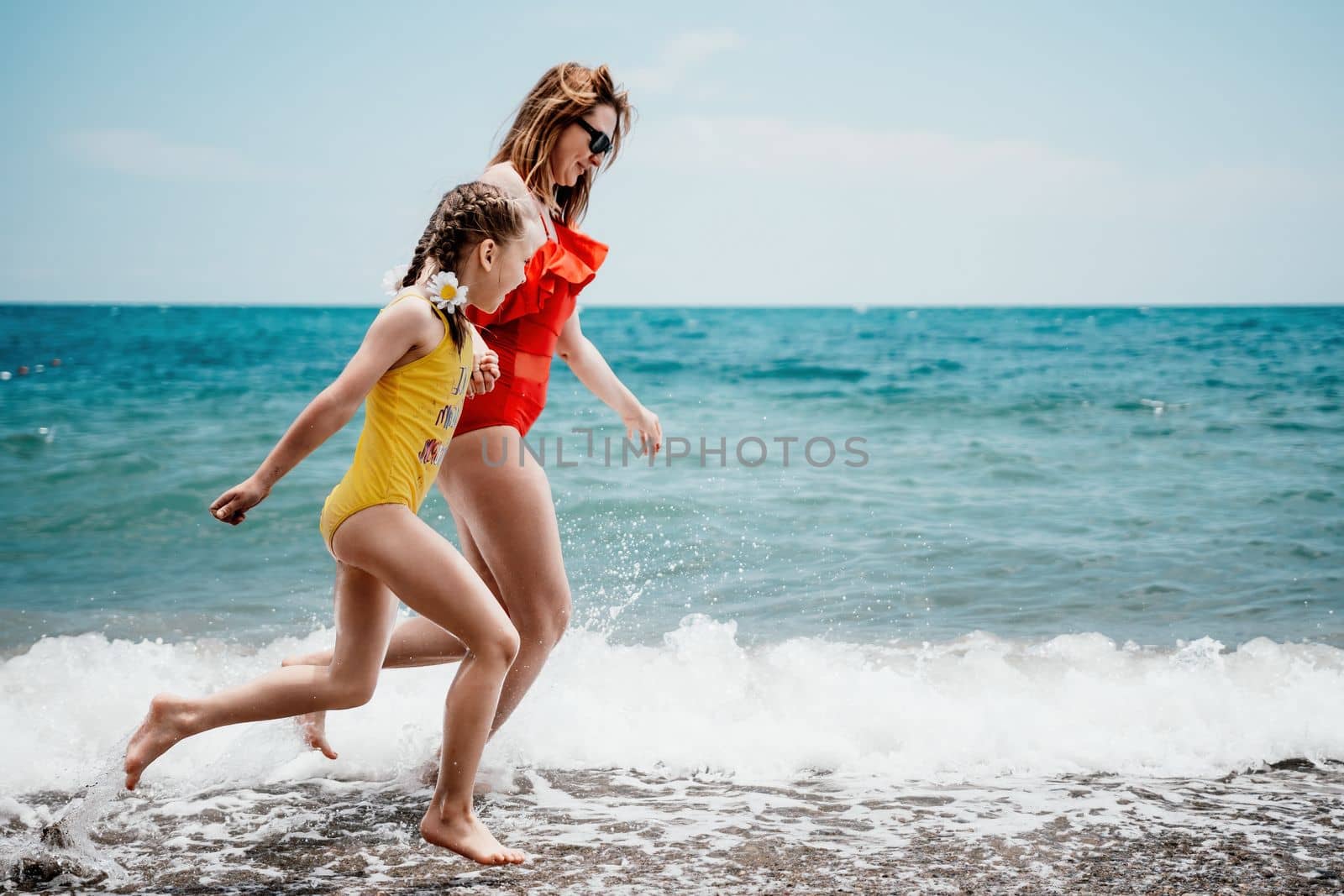 Happy loving family mother and daughter having fun together on the beach. Mum playing with her kid in holiday vacation next to the ocean - Family lifestyle and love concept by panophotograph