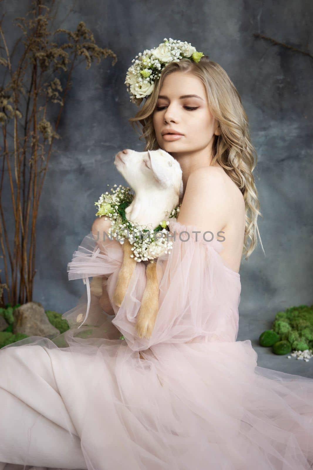 A young blonde woman in an airy pink dress with a white kid. Spring portrait of a woman