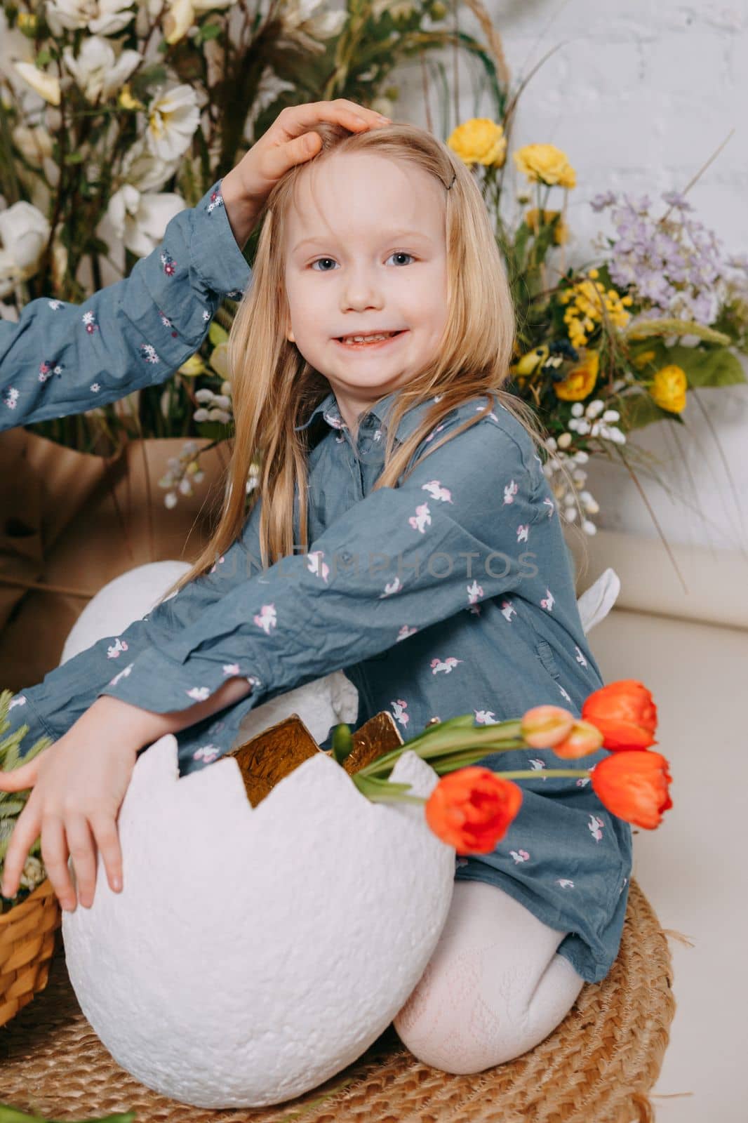 Two girls in a beautiful Easter photo zone with flowers, eggs, chickens and Easter bunnies. Happy Easter holiday