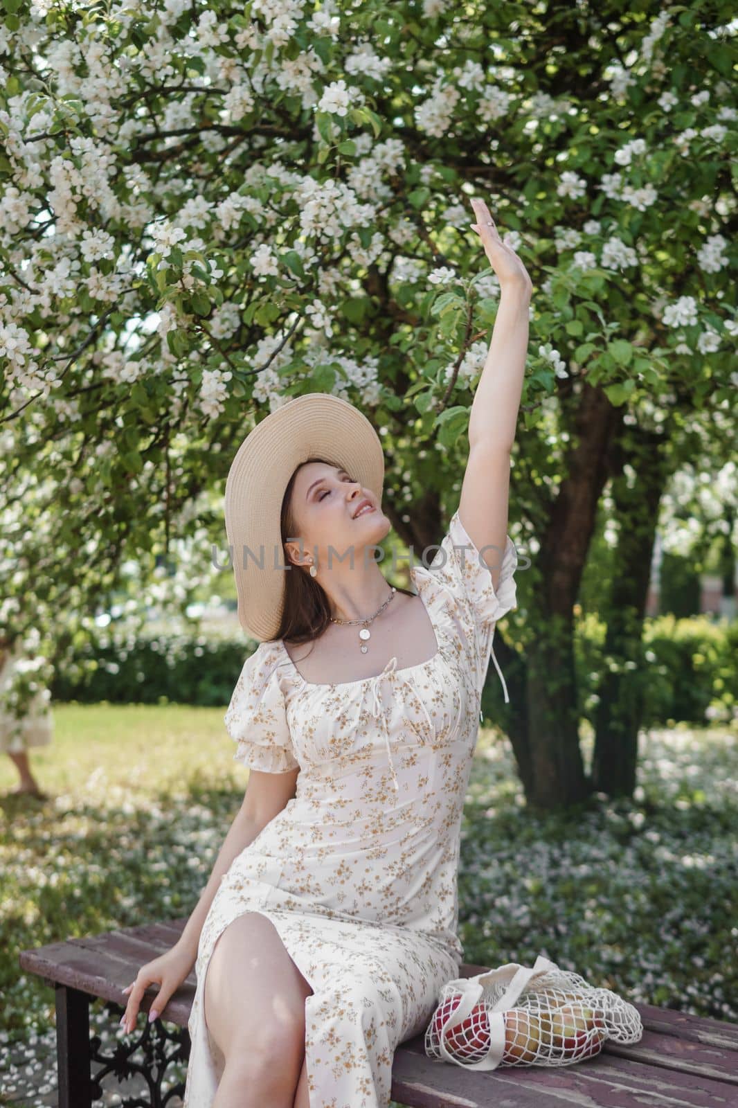 An attractive long-haired woman walks in the spring in the park of blooming apple trees. Spring portrait of a woman