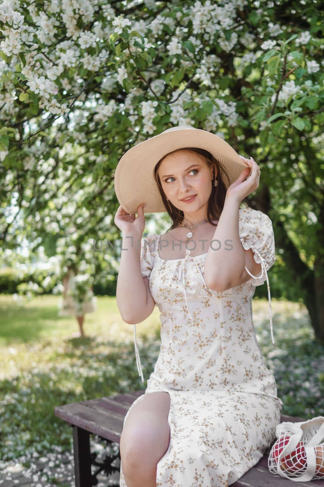 An attractive long-haired woman walks in the spring in the park of blooming apple trees. Spring portrait of a woman