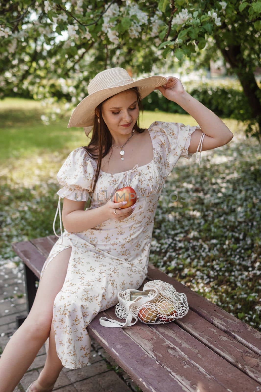 An attractive long-haired woman walks in the spring in the park of blooming apple trees. Spring portrait of a woman