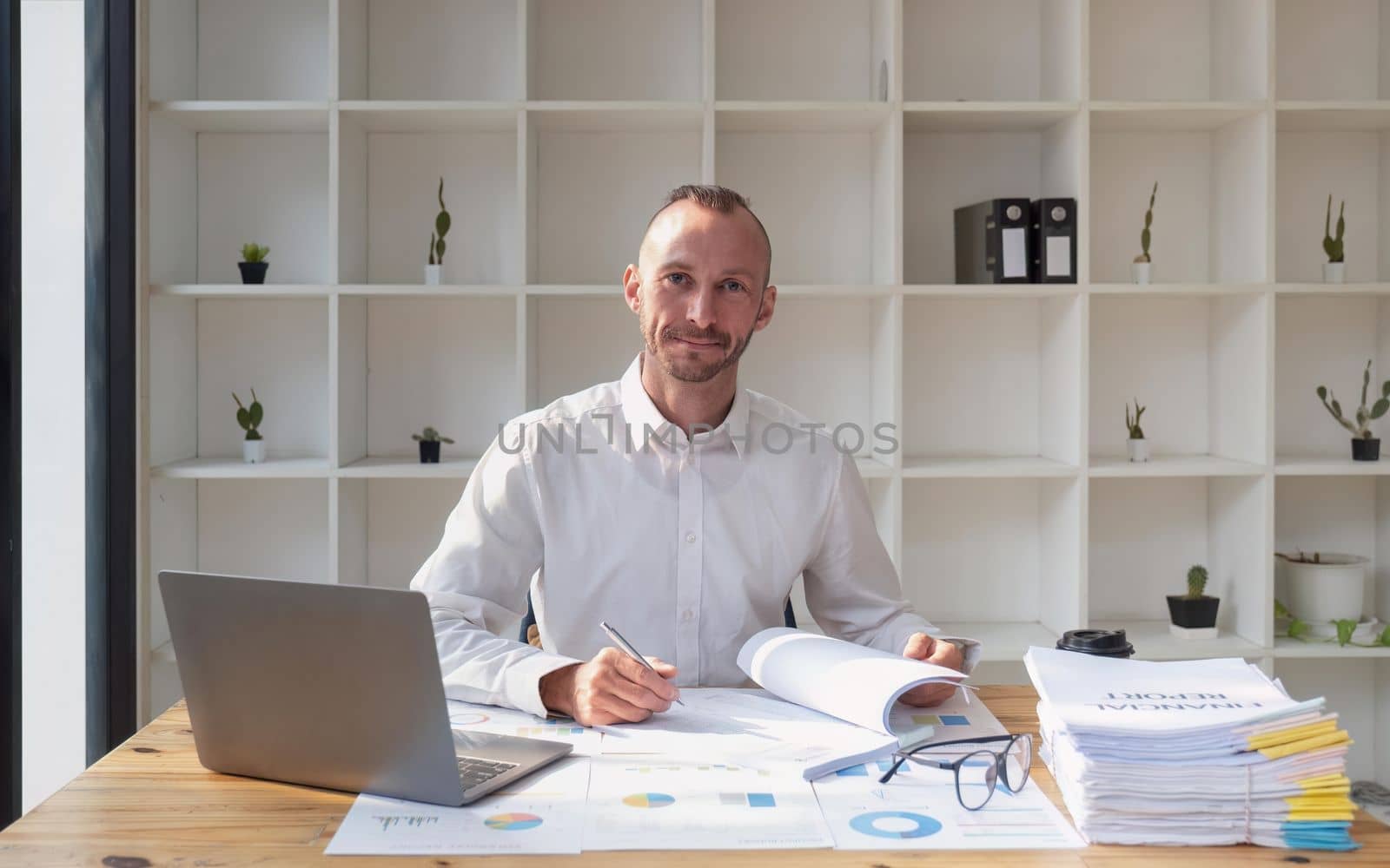 Young business man working at office with laptop and papers on desk.