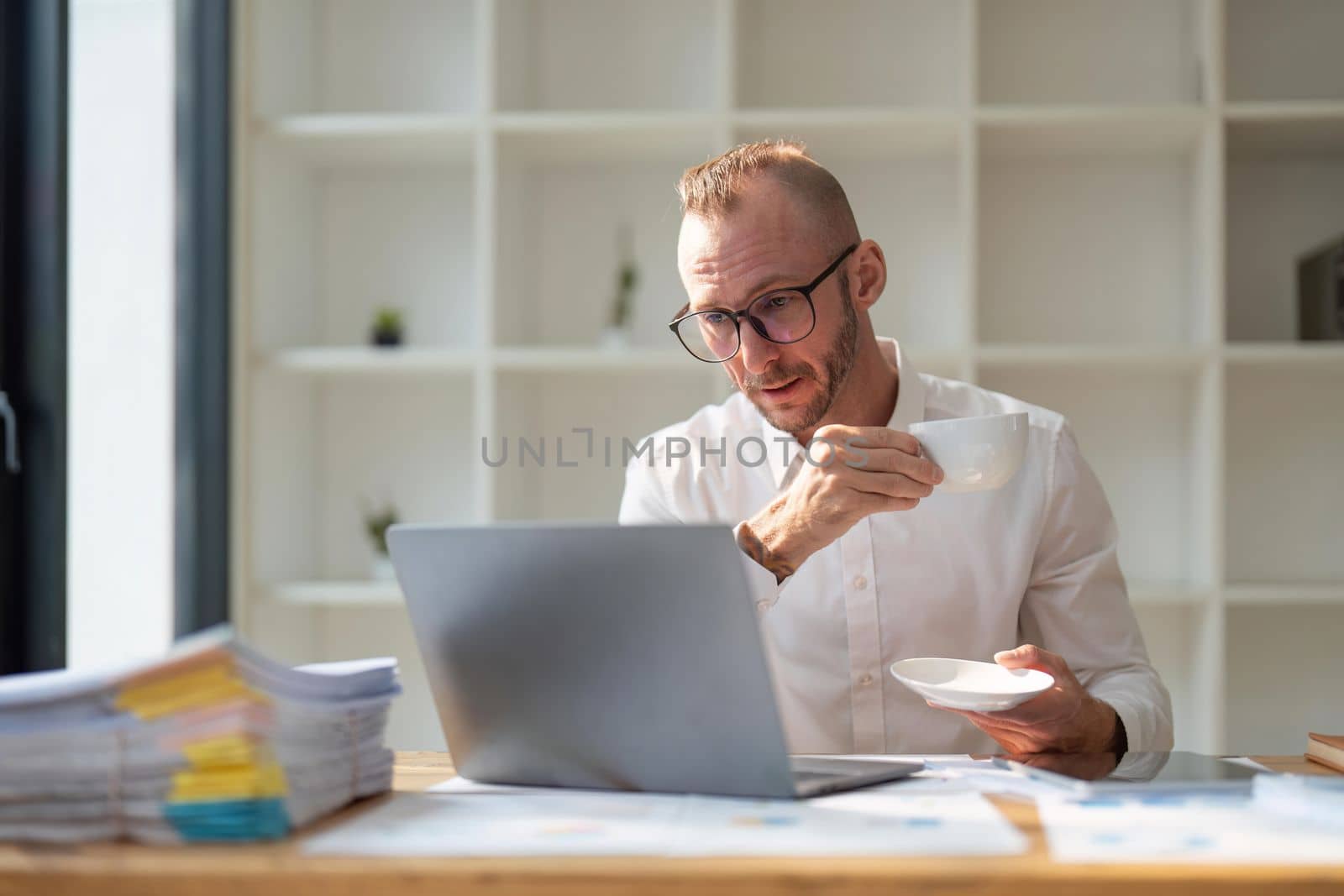 Businessman drinking coffee and working in office.