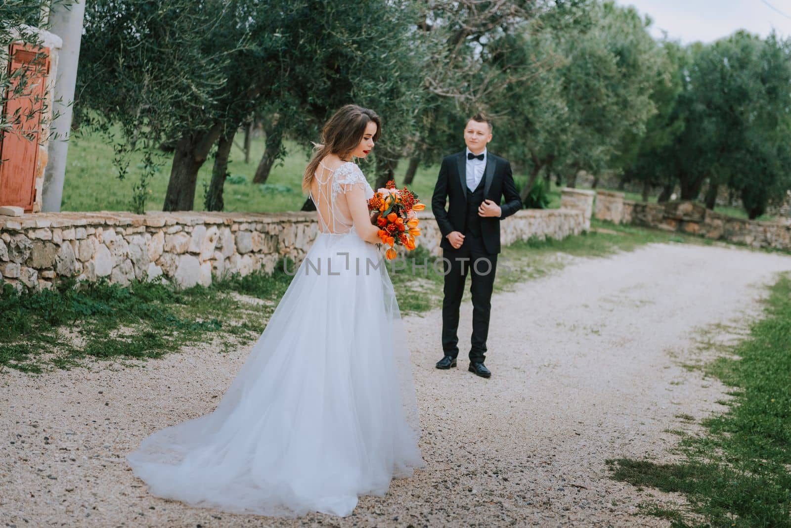 Happy stylish smiling couple walking in Tuscany, Italy on their wedding day. The bride and groom walk down the street by the hands. A stylish young couple walks. Husband and wife communicate nicely. Lovers run through the streets of the city.