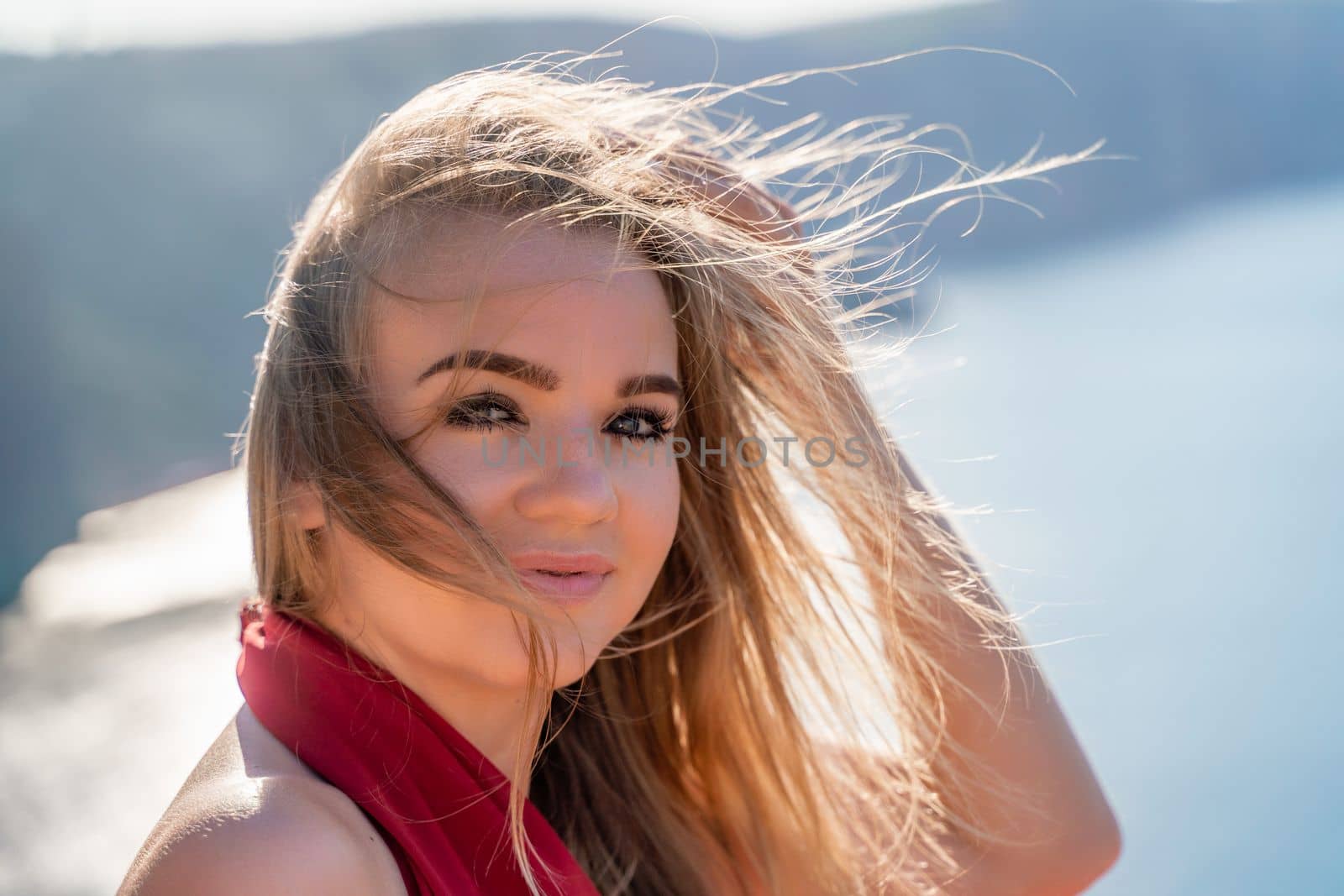 A woman in a red flying dress fluttering in the wind, against the backdrop of the sea. by Matiunina