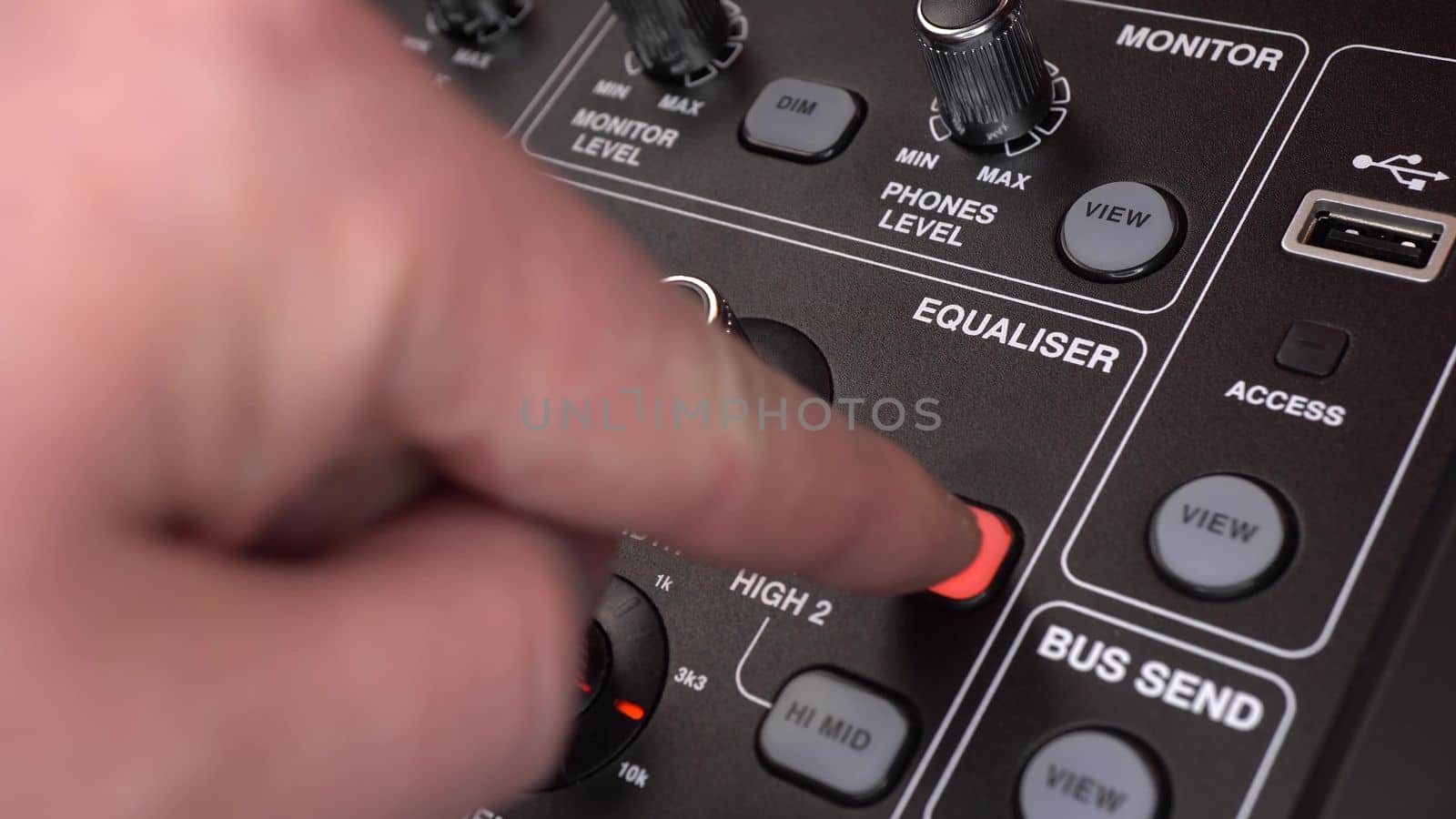 A sound engineer adjusts frequencies on a digital audio mixer. The man presses the buttons and turns the toggle switches on the sound console. Close-up of a man's hand. 4k