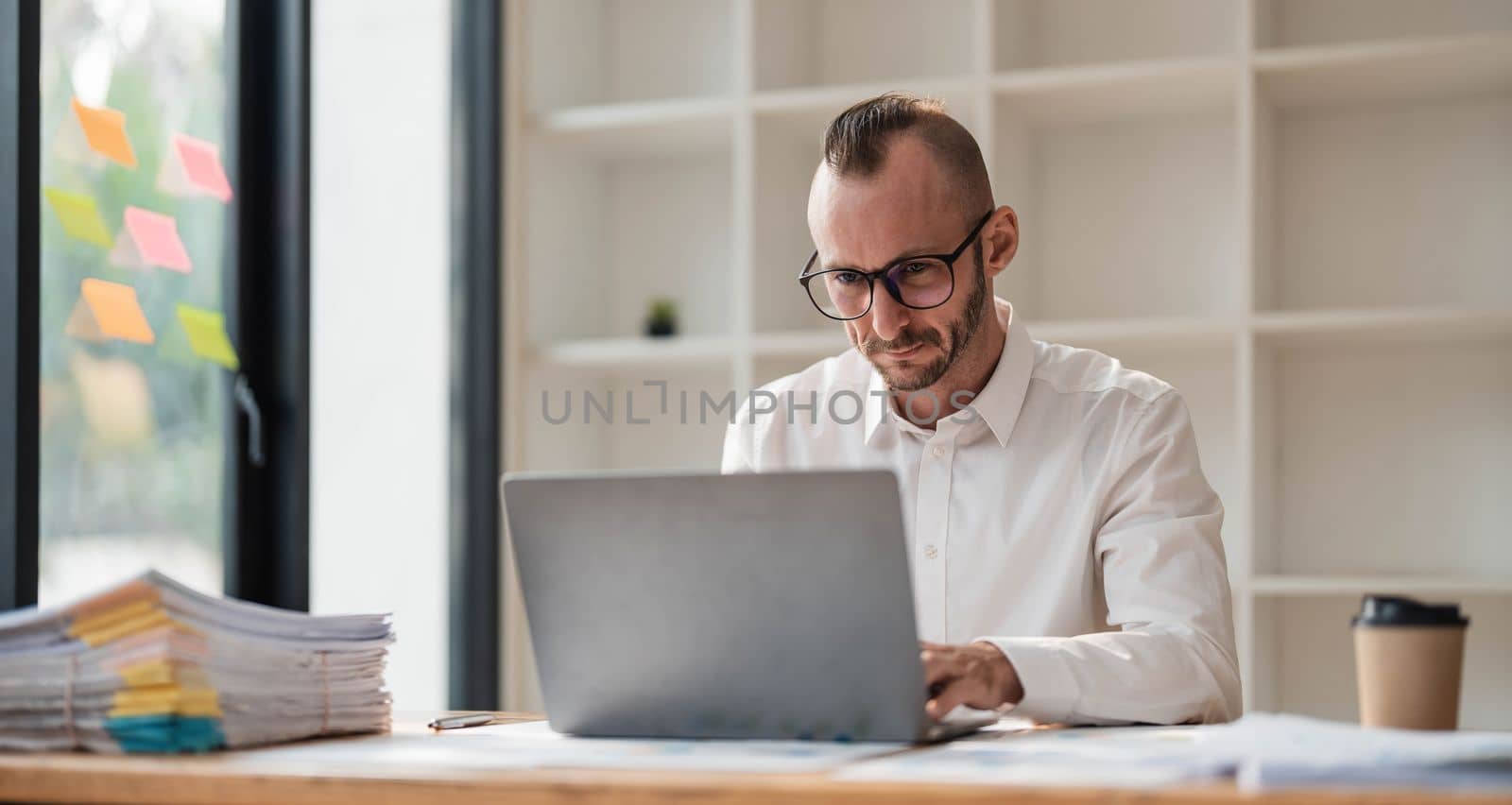 Businessman using laptop computer in office. Happy middle aged man, entrepreneur, small business owner working online. by wichayada
