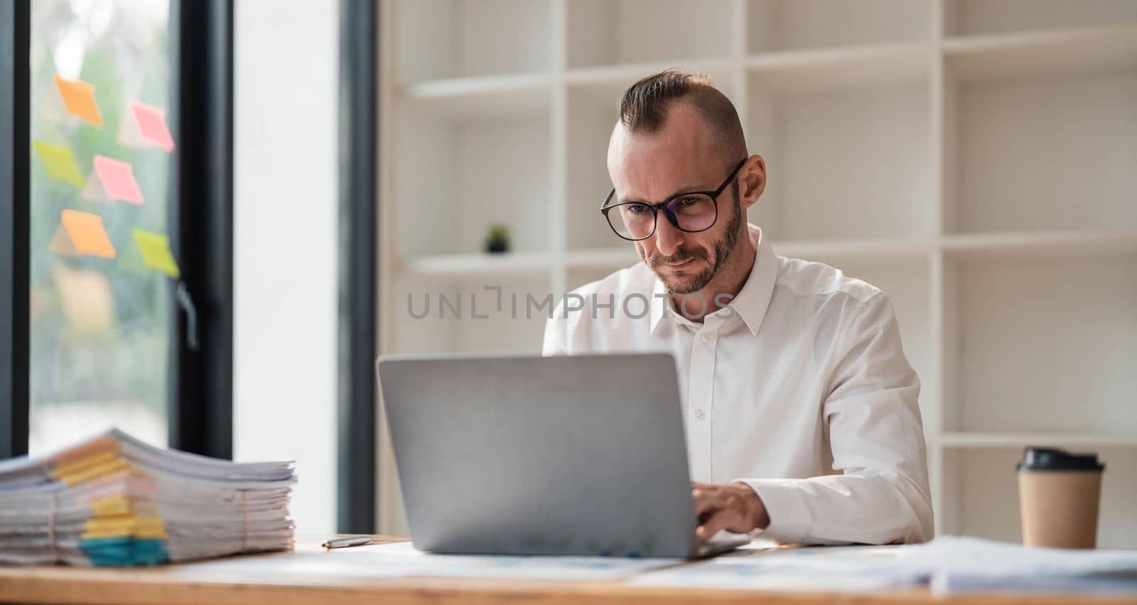 Businessman using laptop computer in office. Happy middle aged man, entrepreneur, small business owner working online...