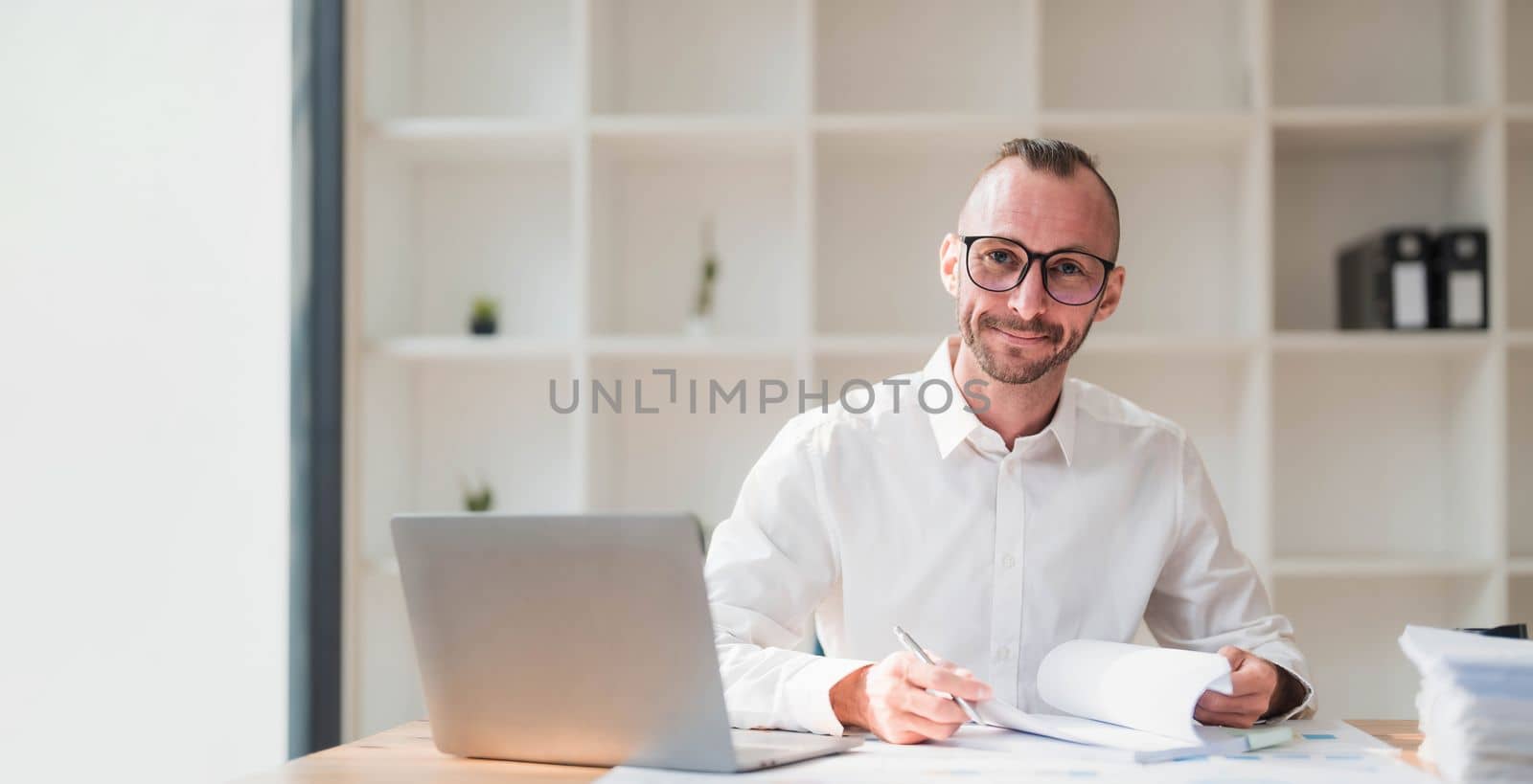 Businessman using laptop computer in office. Happy middle aged man, entrepreneur, small business owner working online. by wichayada