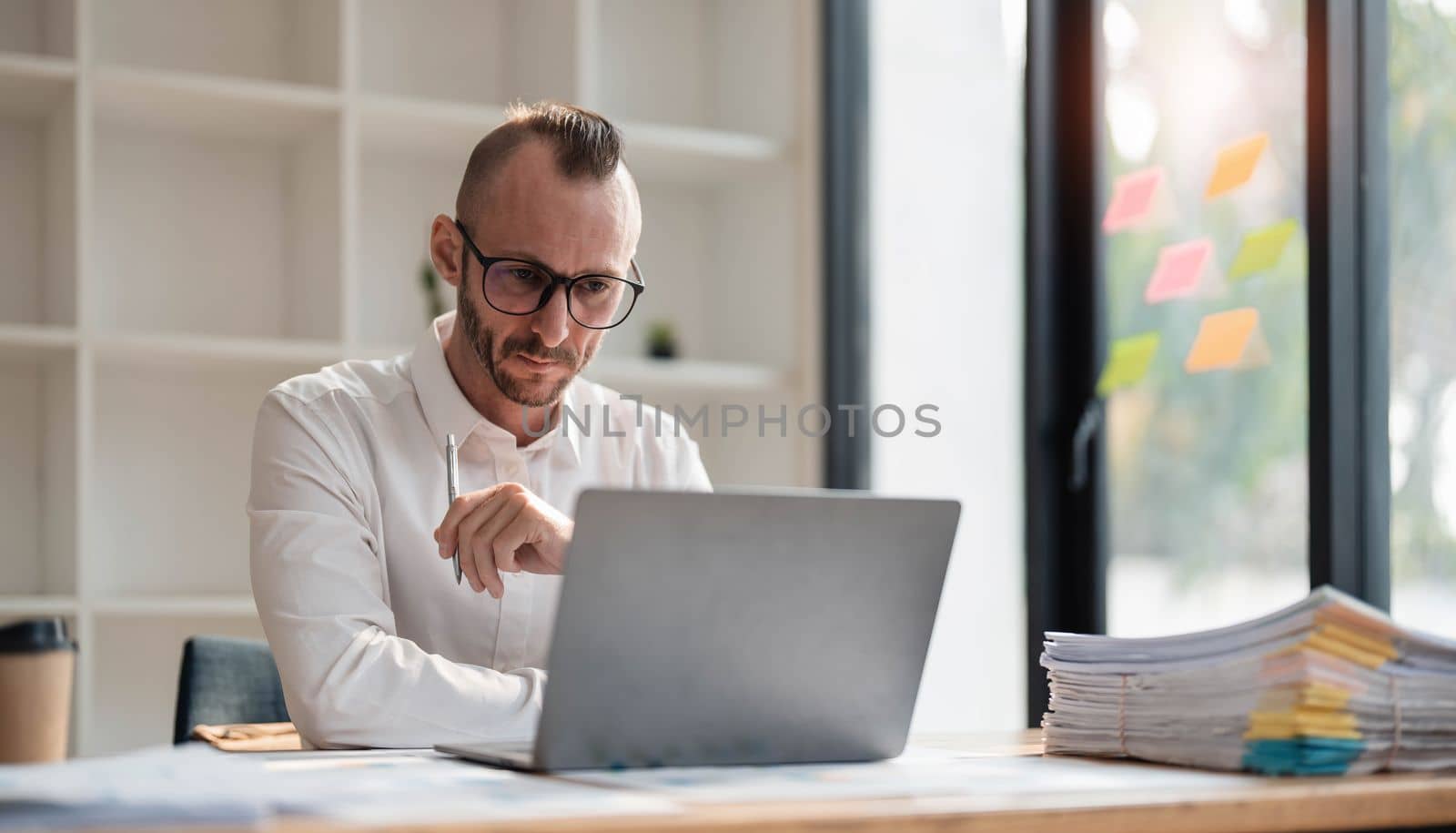 Businessman using laptop computer in office. Happy middle aged man, entrepreneur, small business owner working online. by wichayada
