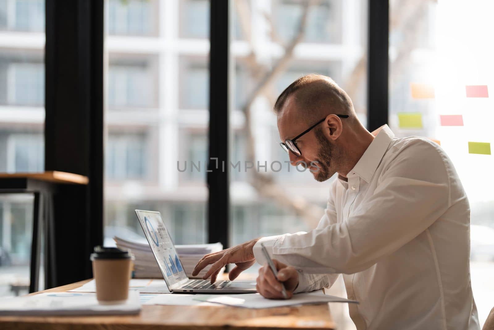 Businessman using laptop computer in office. Happy middle aged man, entrepreneur, small business owner working online...