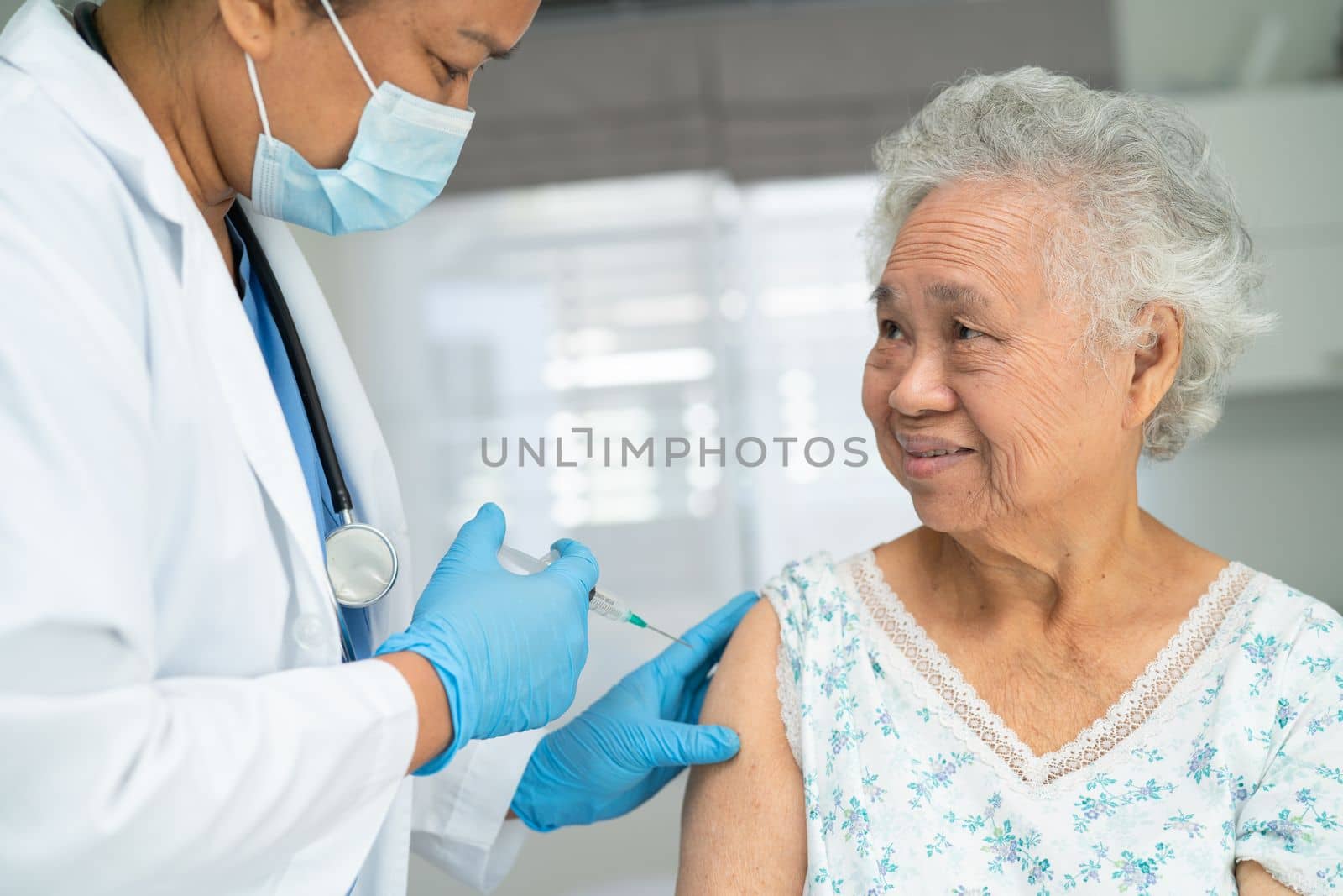 Elderly Asian senior woman wearing face mask getting covid19 or coronavirus vaccine by doctor make injection.