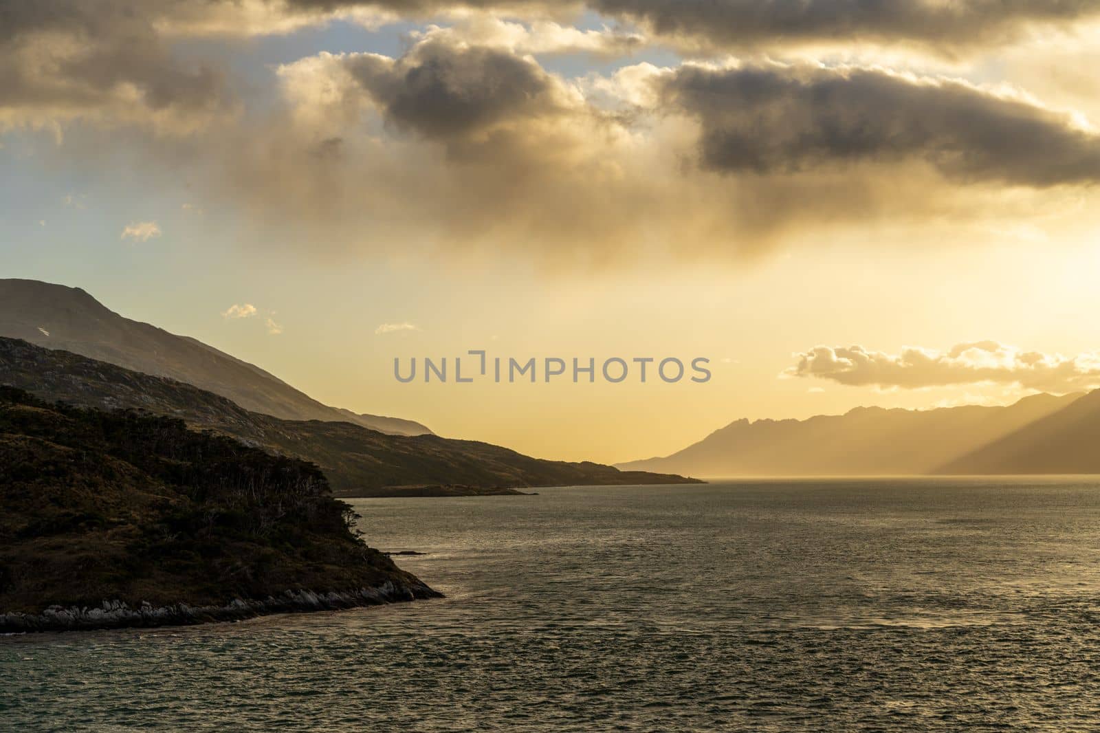 Cruise ship sailing between mountains in Glacier Alley of Beagle channel in Chile at sunrise