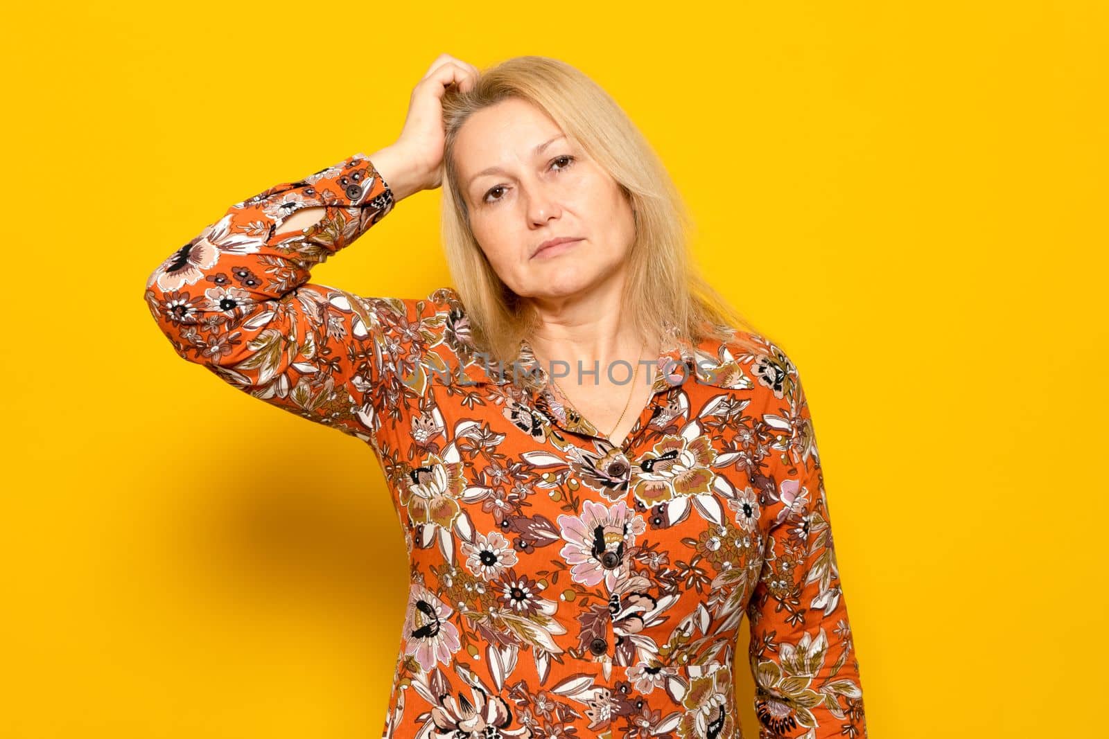 Woman scratching her head with doubts and confusion isolated on yellow background. Idea, hair scratch and difficult choice for model in studio with frustrated expression on her face