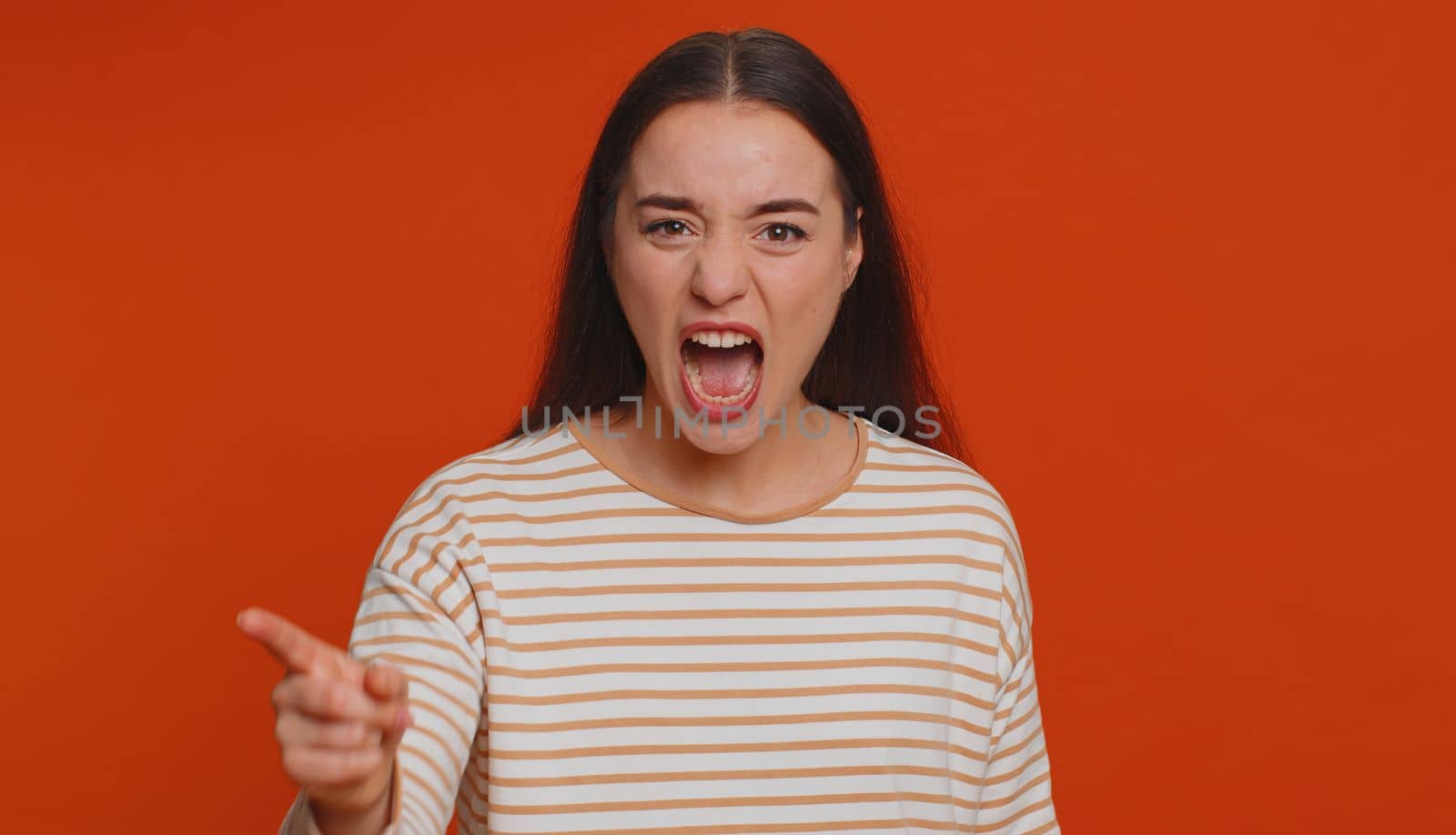 Quarrel. Displeased pretty young woman gesturing hands with irritation and displeasure, blaming scolding for failure, asking why this happened. Millennial girl isolated on red studio background