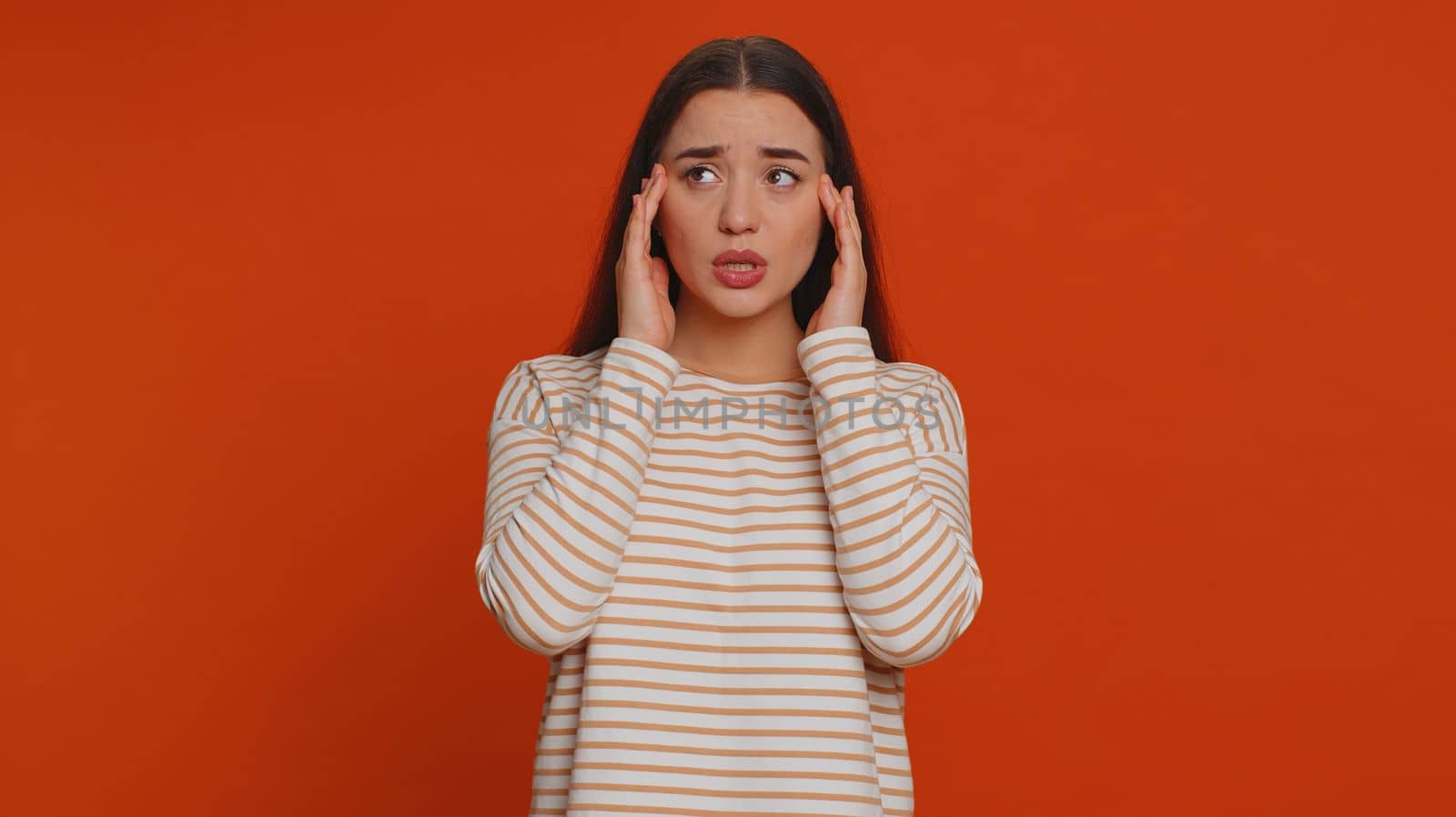 Hipster young pretty woman in pullover rubbing temples to cure headache problem, suffering from tension, migaine, stress, grimacing in pain, high blood pressure isolated alone on red wall background