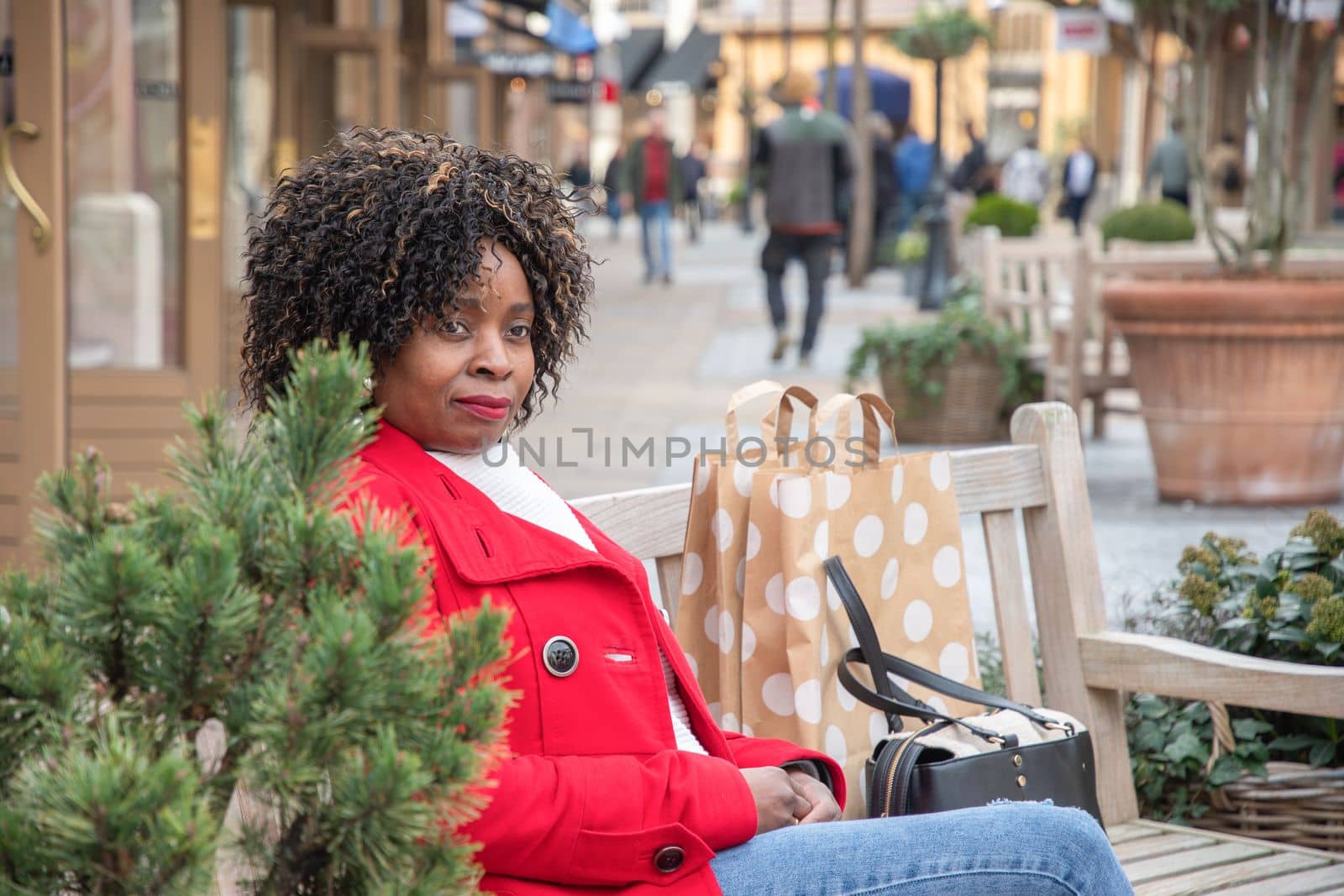 an african woman with big shopping bags relaxing after shopping on outdoor bench by KaterinaDalemans