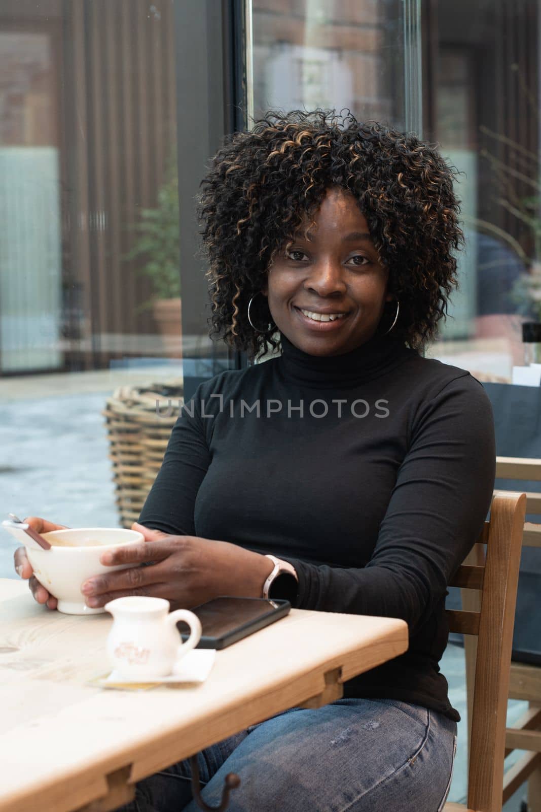 African young woman without makeup sits in a cafe in the morning, having just woken up, and drinks coffee, High quality photo