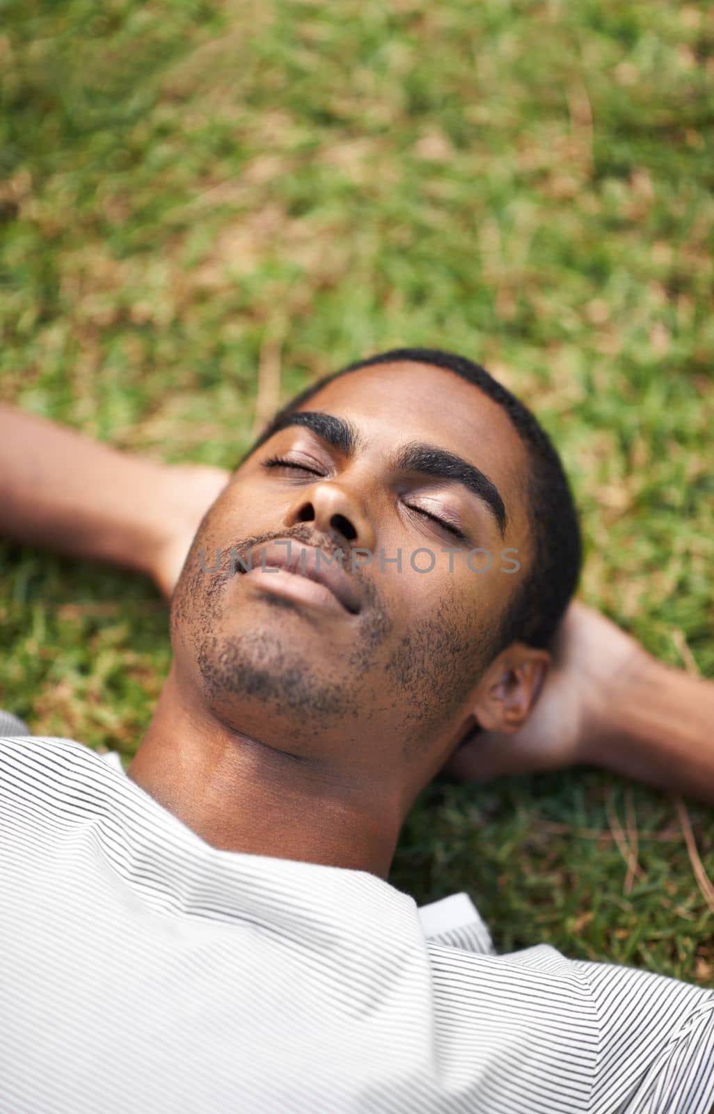 Nap time outdoors. a handsome young man lying on the grass outdoors. by YuriArcurs