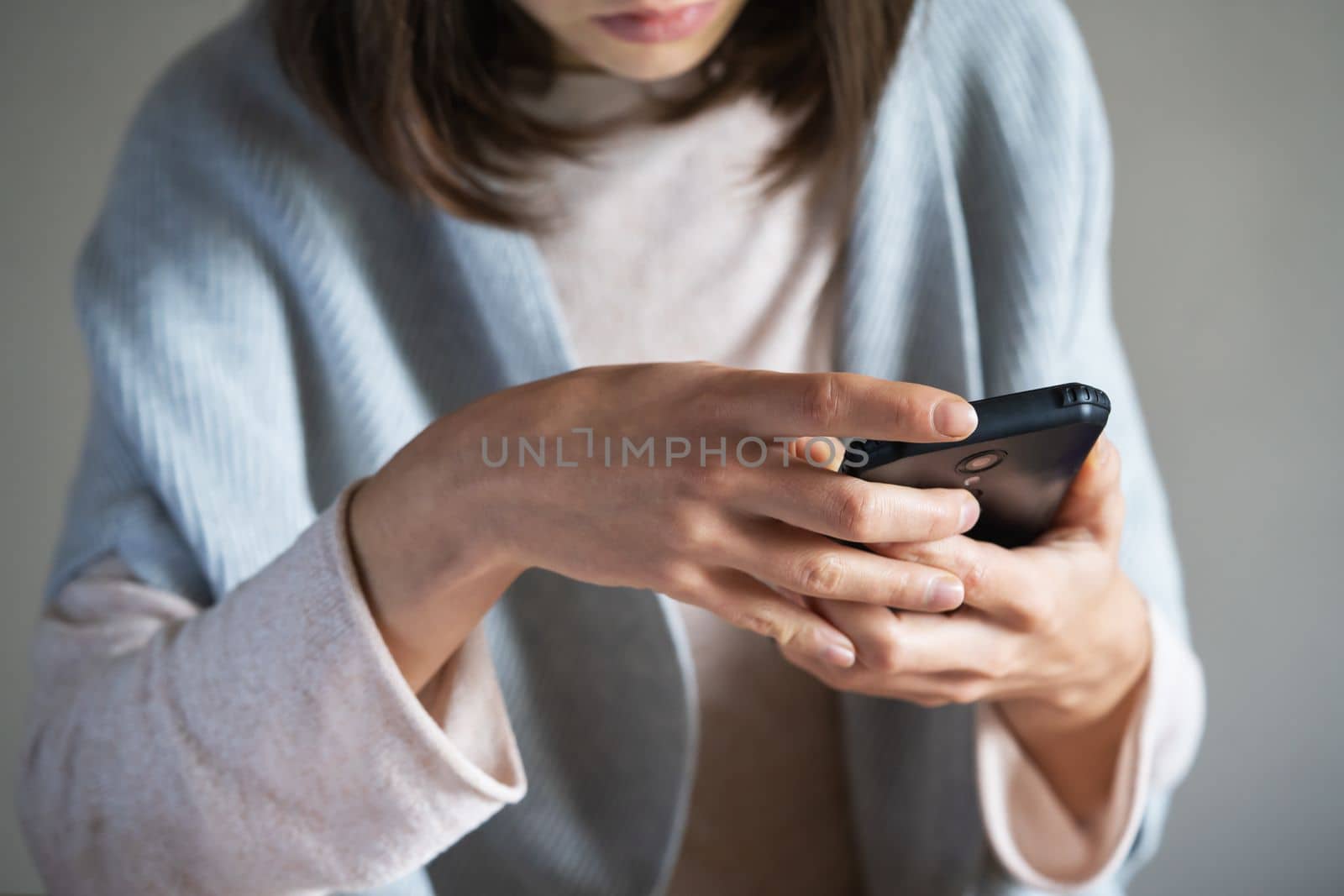 A young girl holds a mobile phone in her hands, sends SMS, chats in social networks, develops her business. A woman uses a smartphone online, close-up view.
