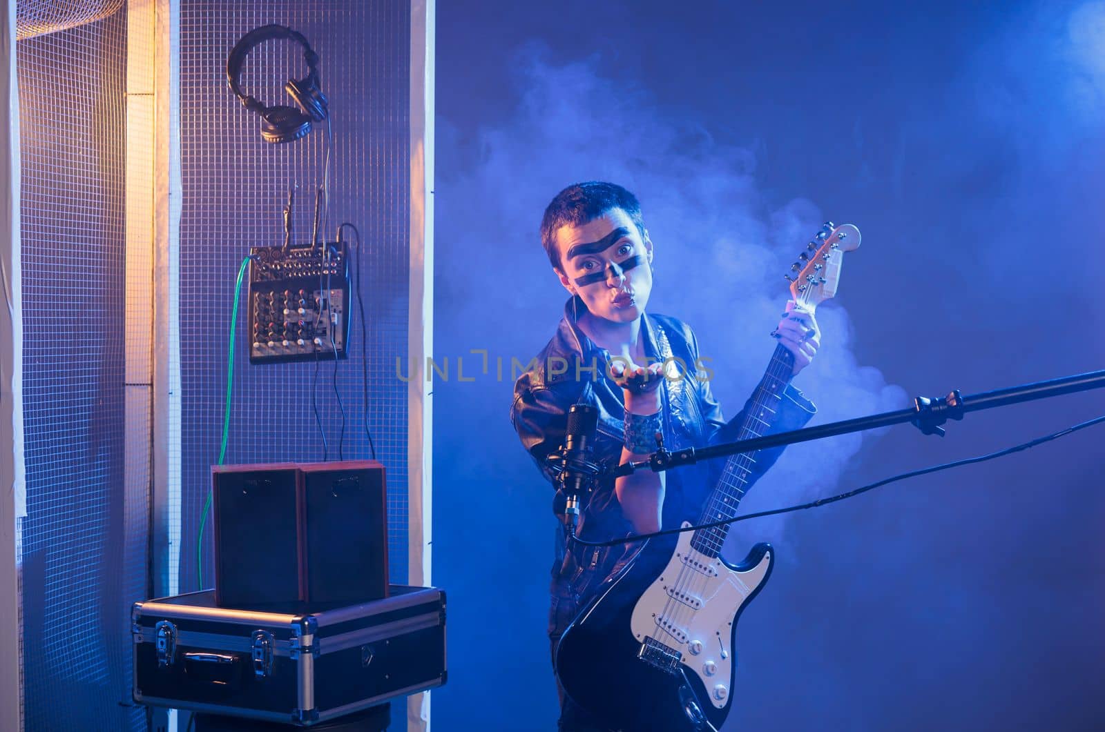 Punk rocker blowing air kisses and acting flirty, playing guitar and having heavy metal style in studio. Sending kiss and being romantic or charming, singing alternative rock music with instrument.