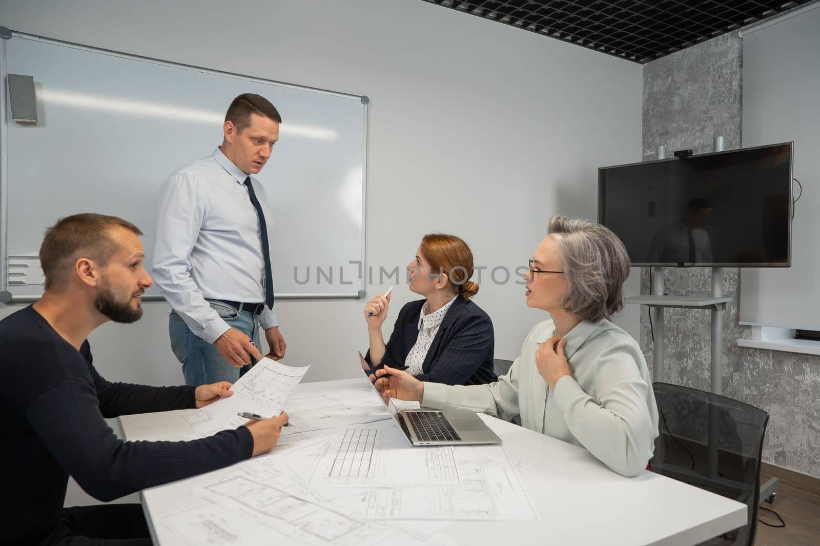 Caucasian man leading a presentation to colleagues at a white board