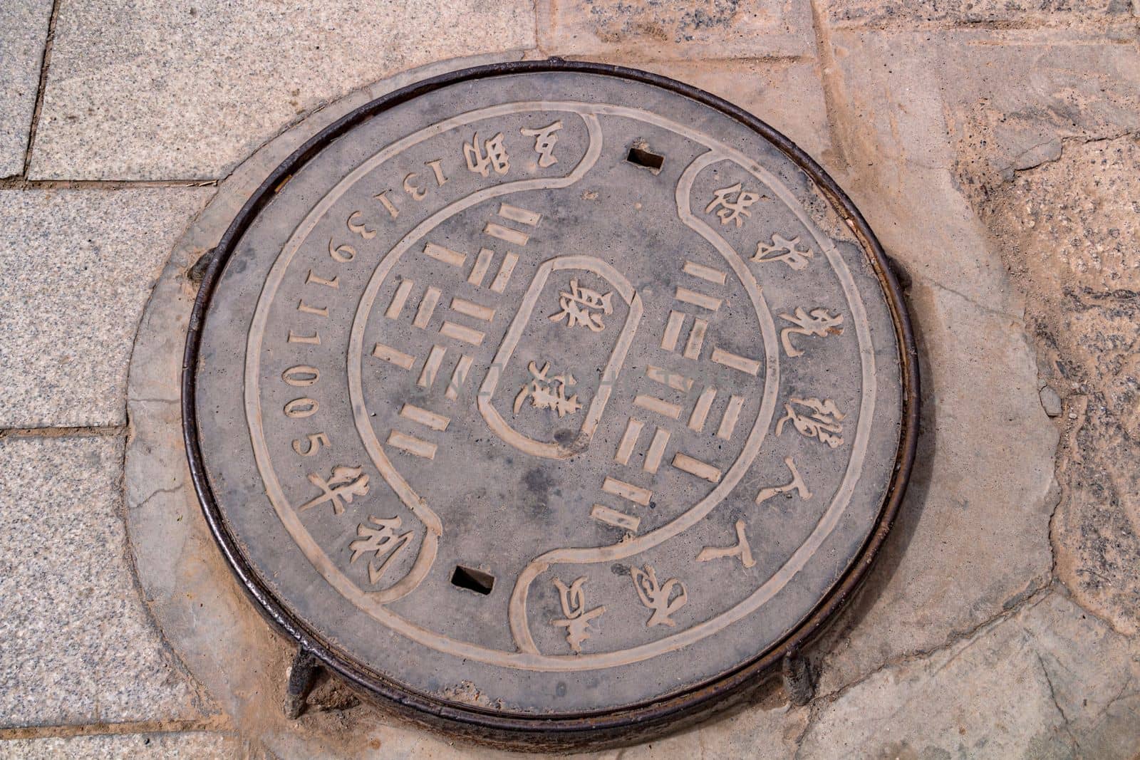 A manhole cover inscribed in Chinese in the courtyard of Kumbum Champa Ling Monastery, Xining, China