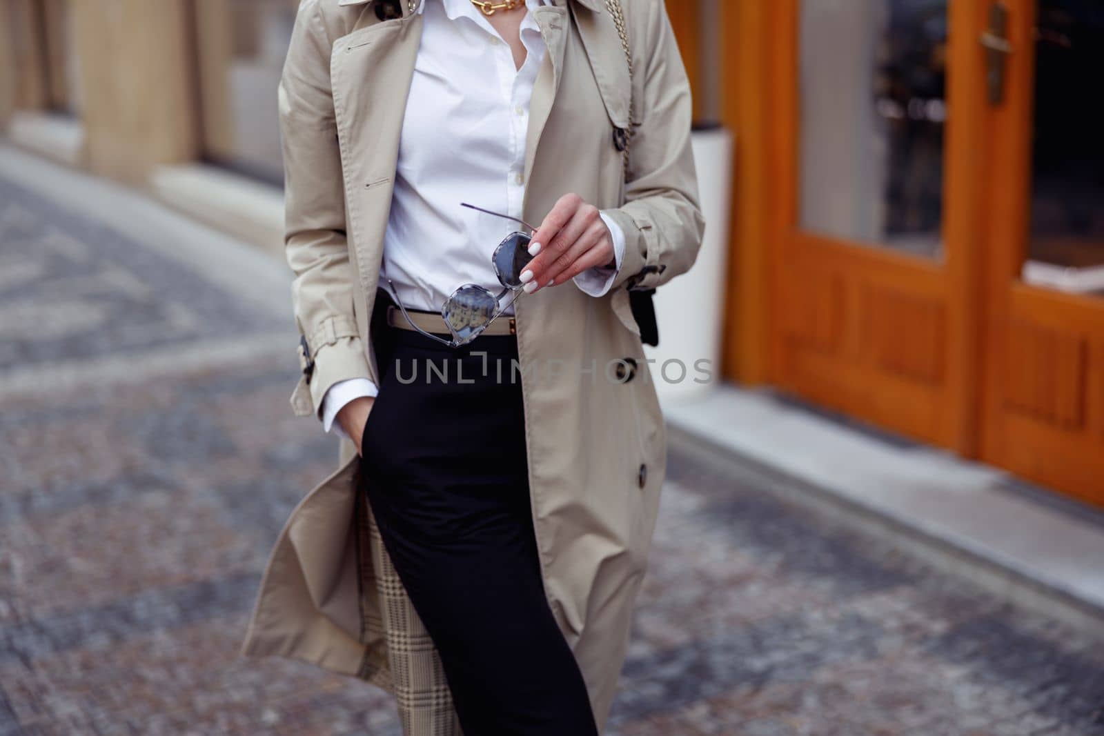 Close up stylish woman in coat with glasses crossing the city street.. High quality photo