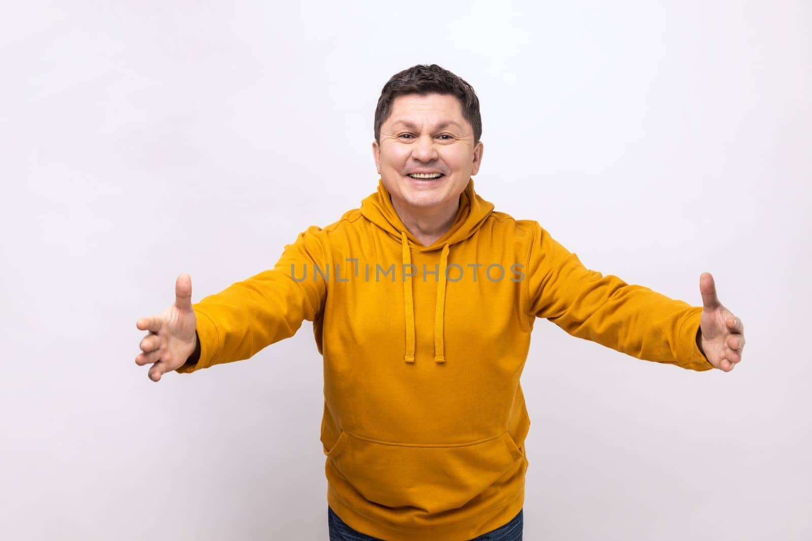 Free hugs. Portrait of friendly kind man stretching hands to camera and smiling broadly, going to embrace, share love, wearing urban style hoodie. Indoor studio shot isolated on white background.