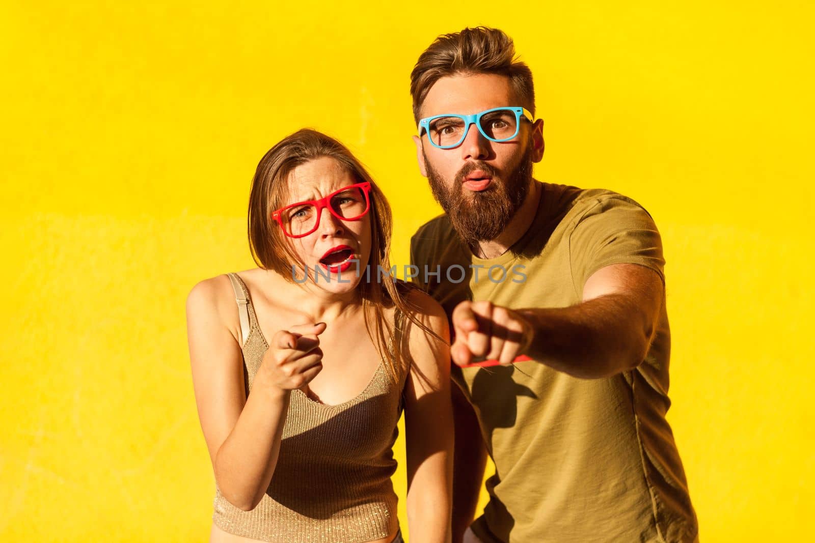 Amazed man and woman standing with shocked face and pointing to camera, having surprised expression. by Khosro1