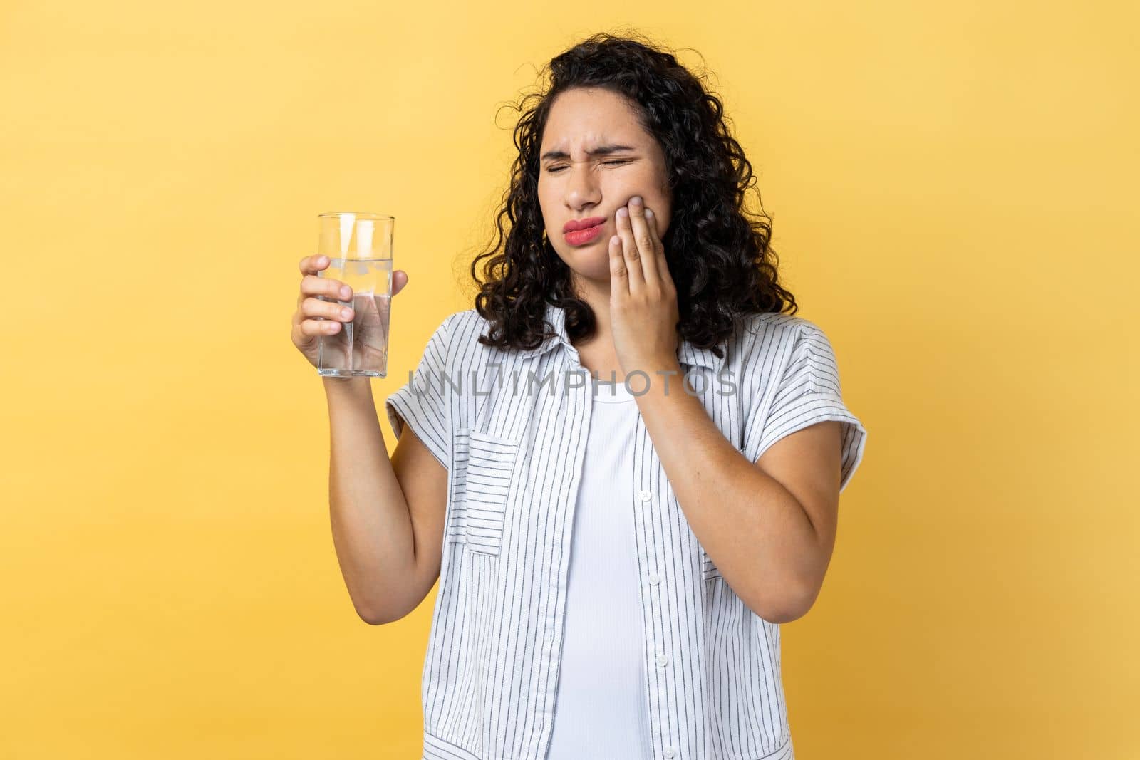 Woman standing and touching his cheek because feeling pain on tooth, after drinking hot tea. by Khosro1