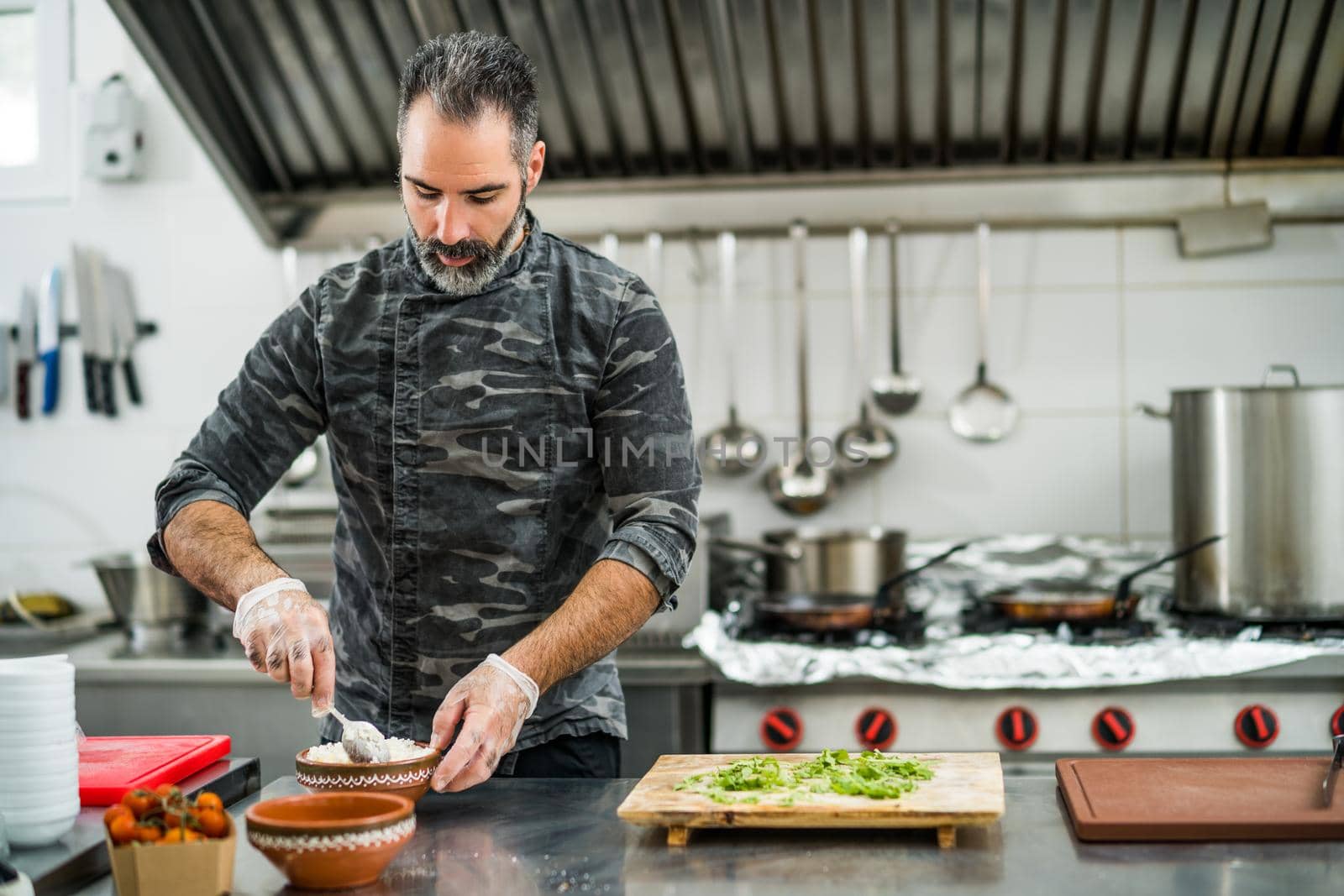 Professional cook is serving meal in restaurant's kitchen.