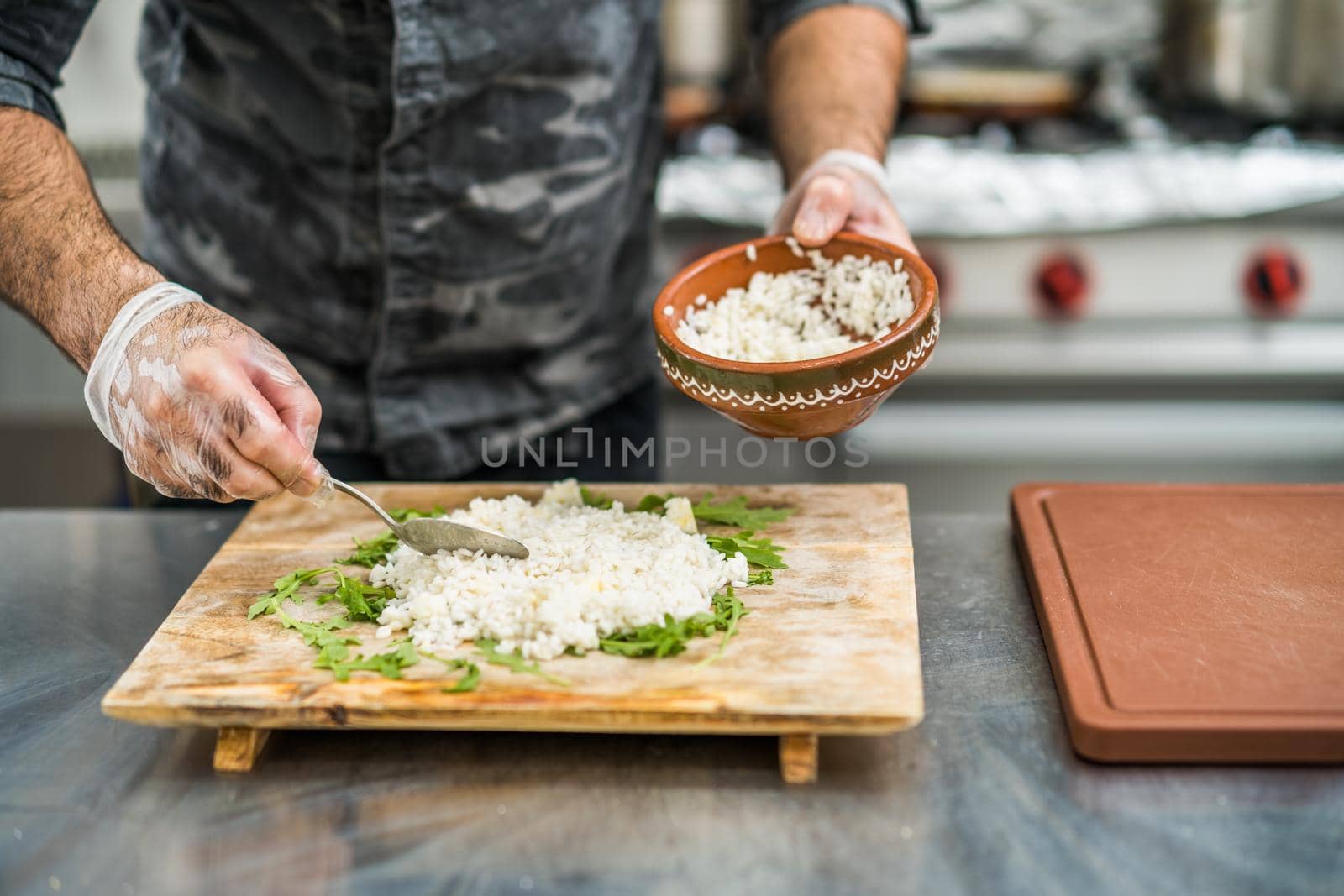 Professional cook is serving meal in restaurant's kitchen.